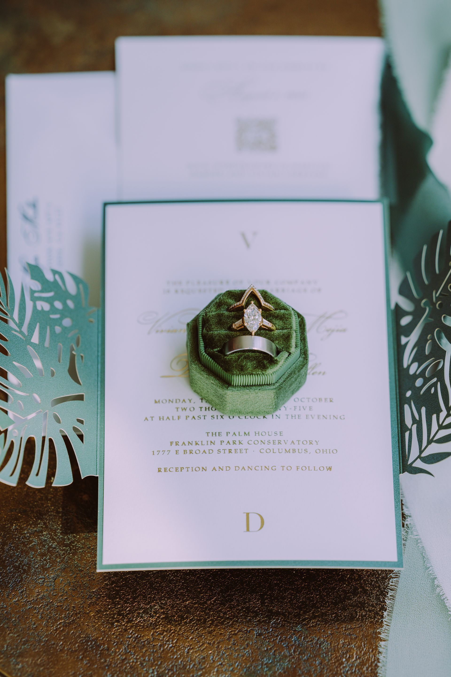 Wedding invitation with ring in a green velvet box, on a white card with gold text. Photo by Kodjo Somana