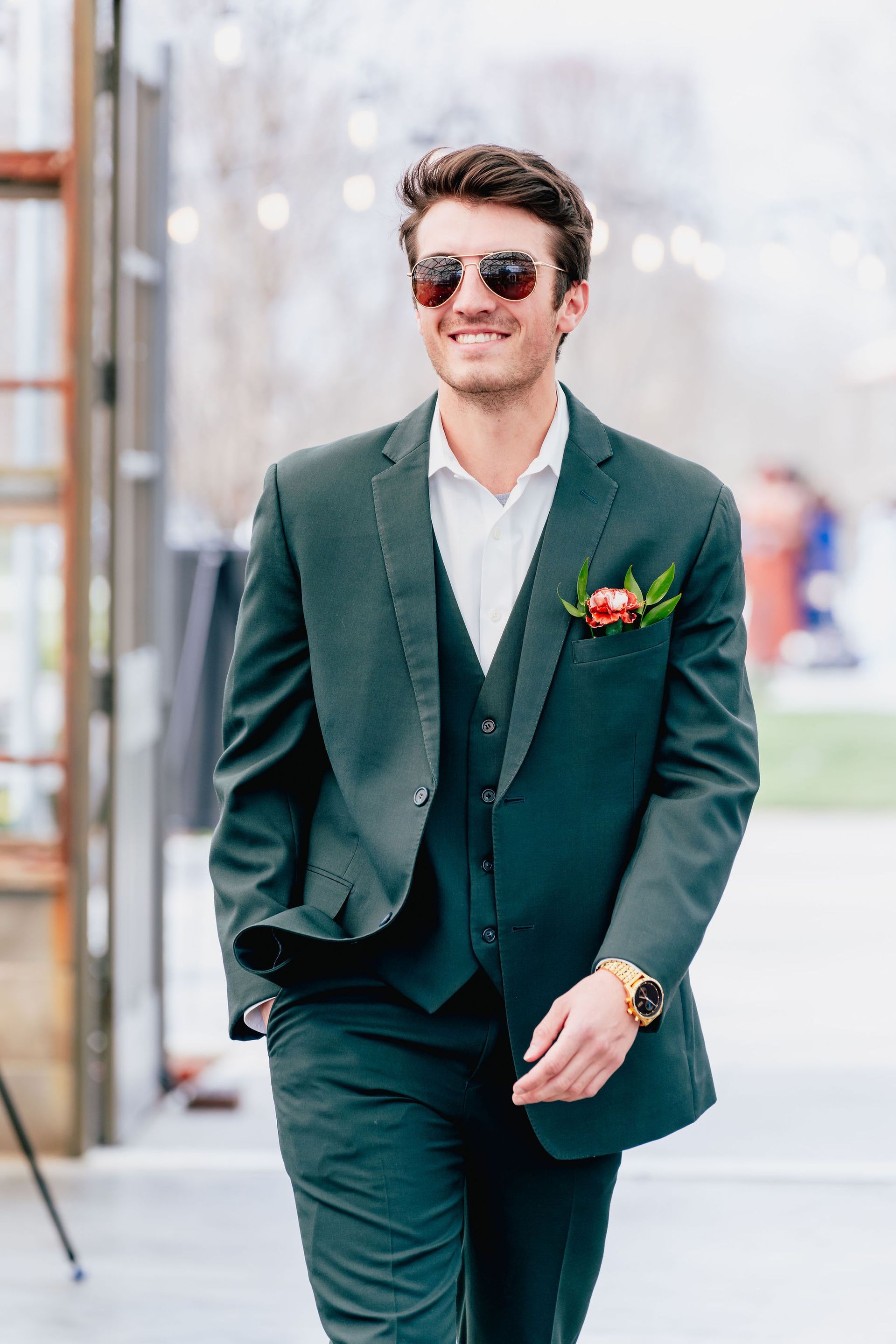 A man in a green suit and sunglasses is walking down the street.