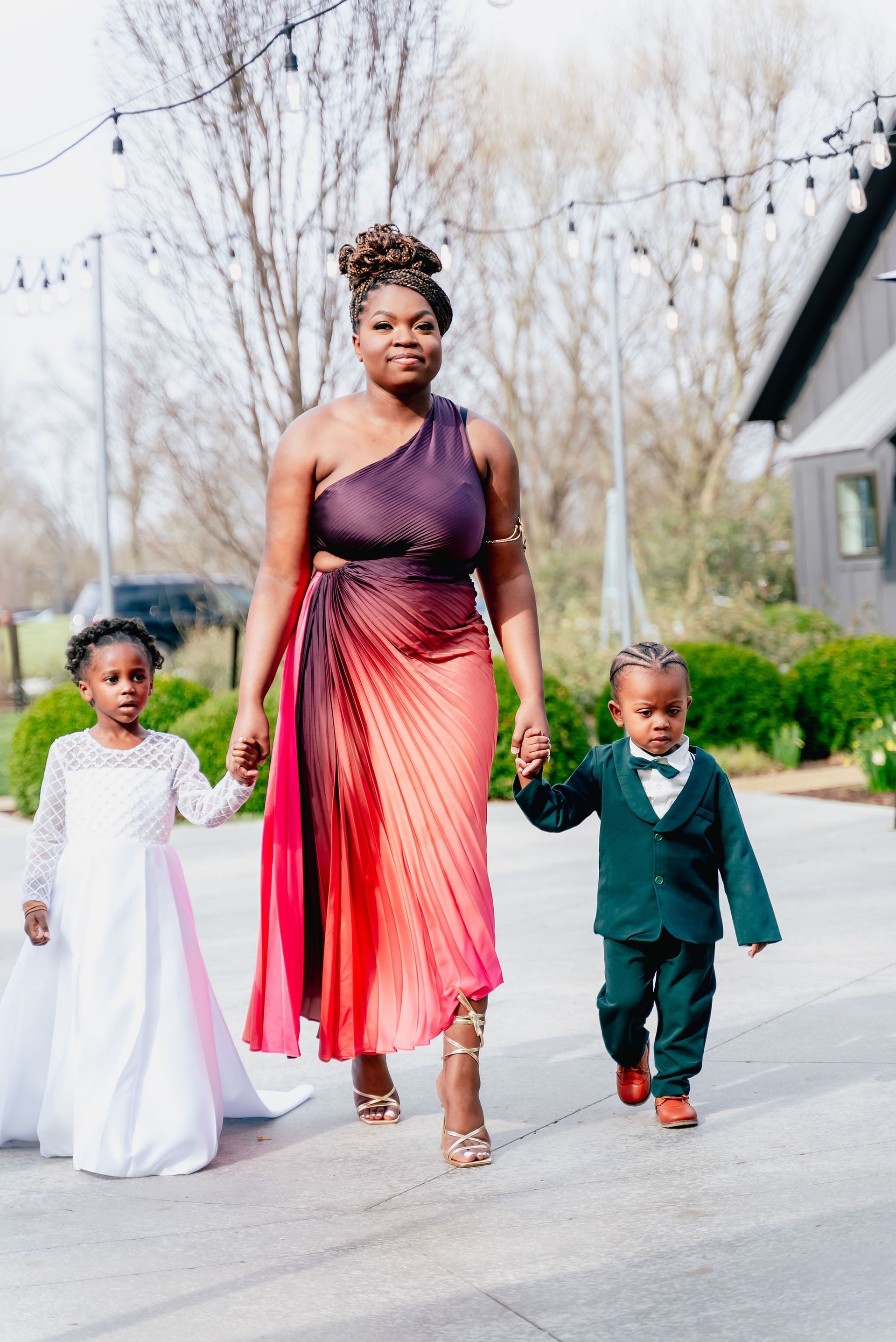 A woman and two children are walking down the street holding hands.