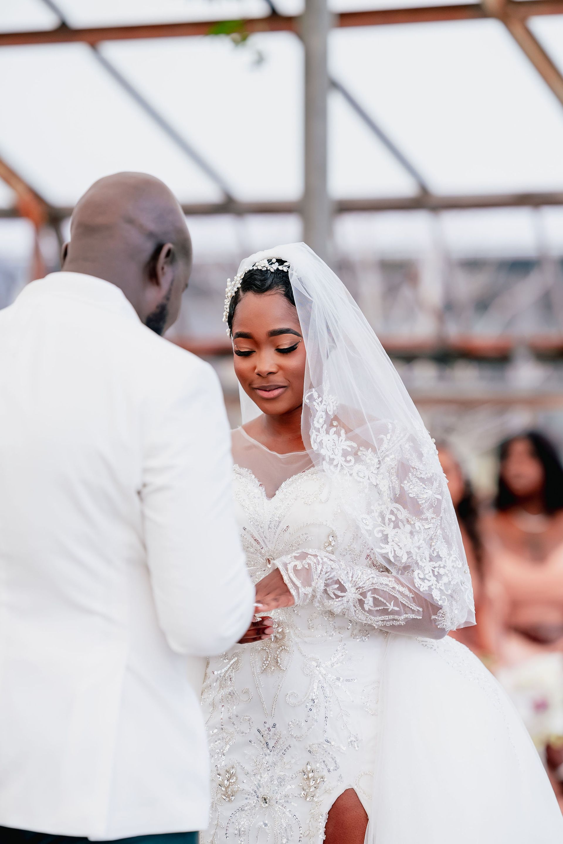 A bride and groom are dancing at their wedding in a greenhouse.