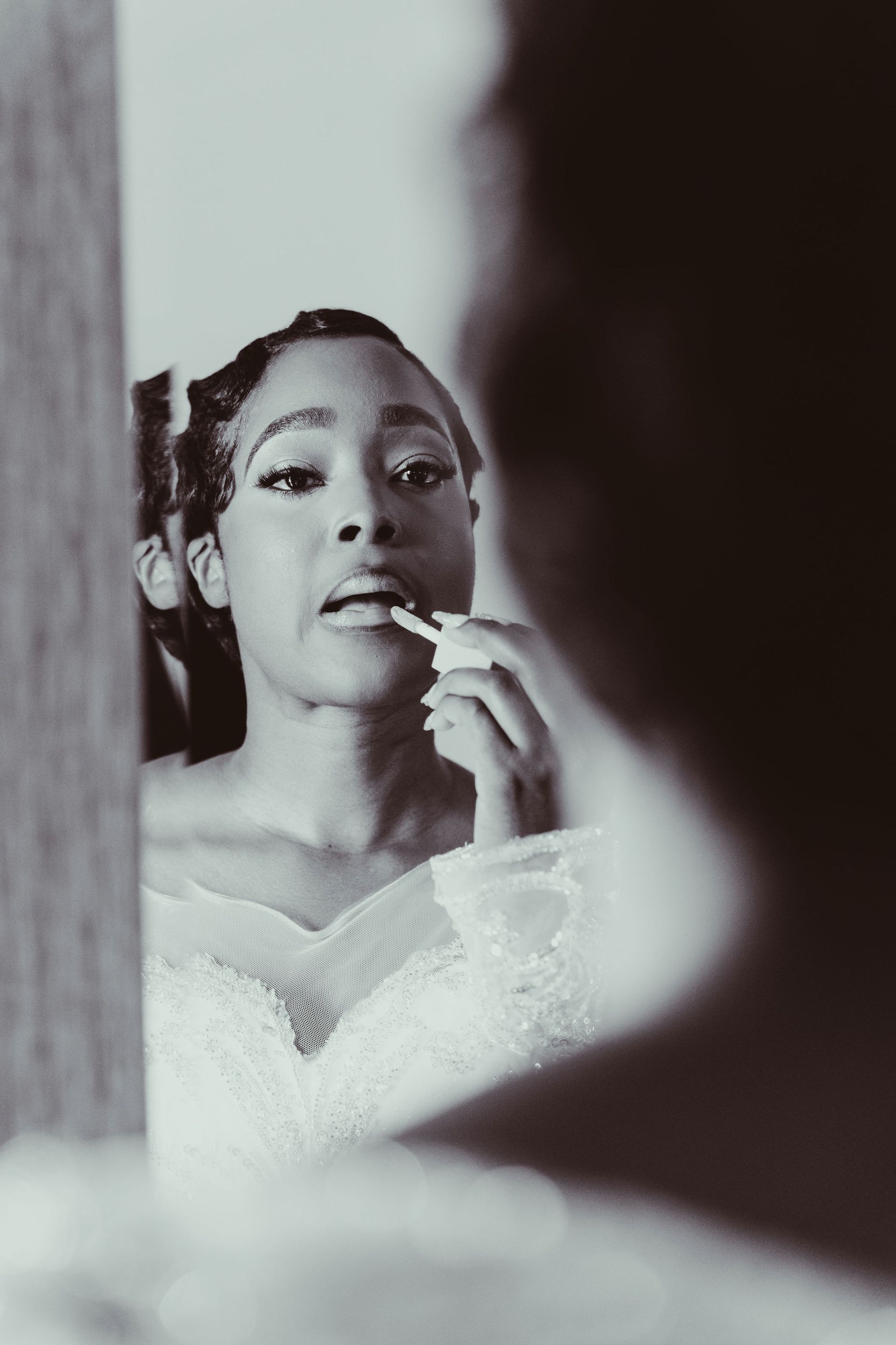 A woman is applying lipstick in front of a mirror.