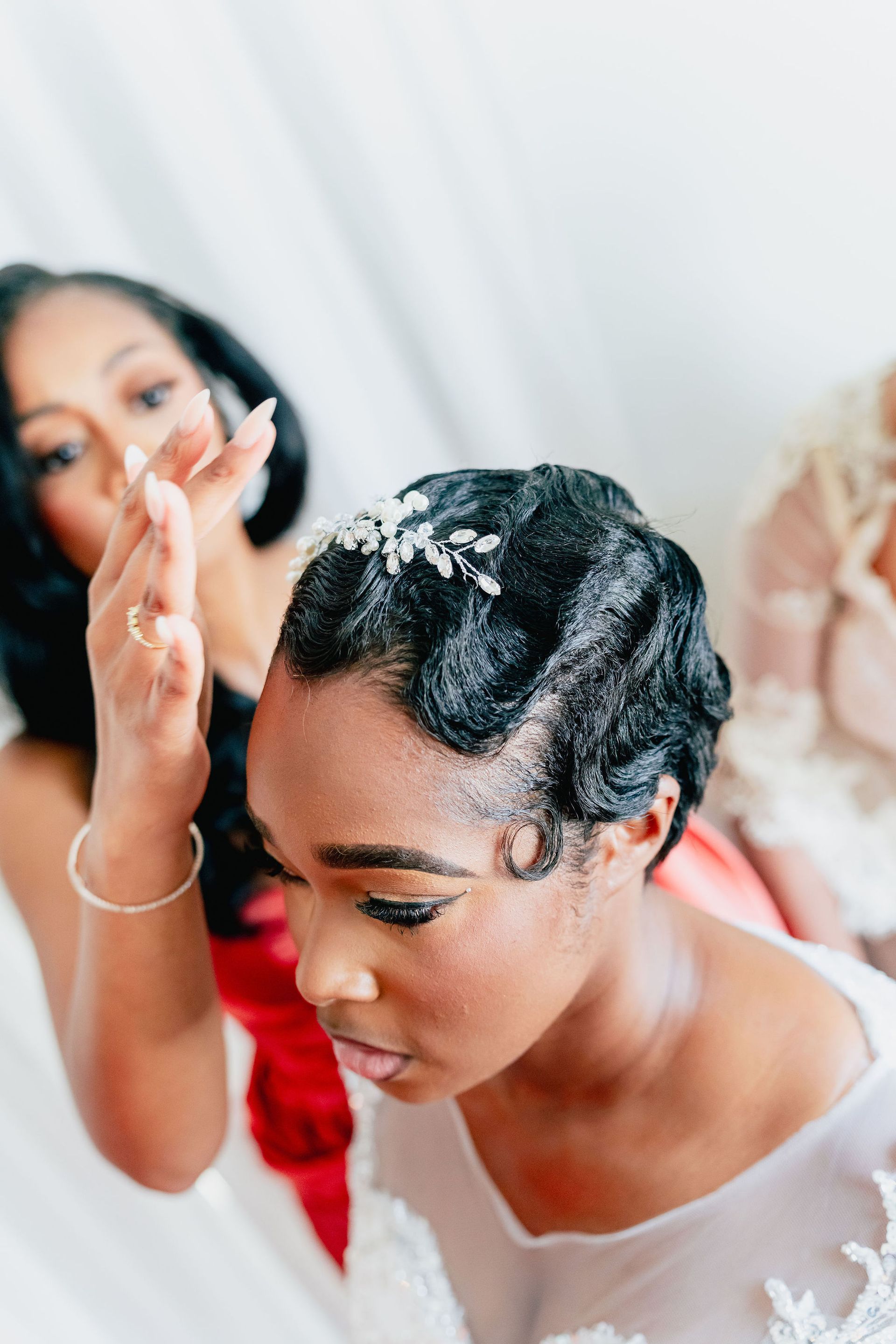 A woman is fixing another woman 's hair in front of a mirror.