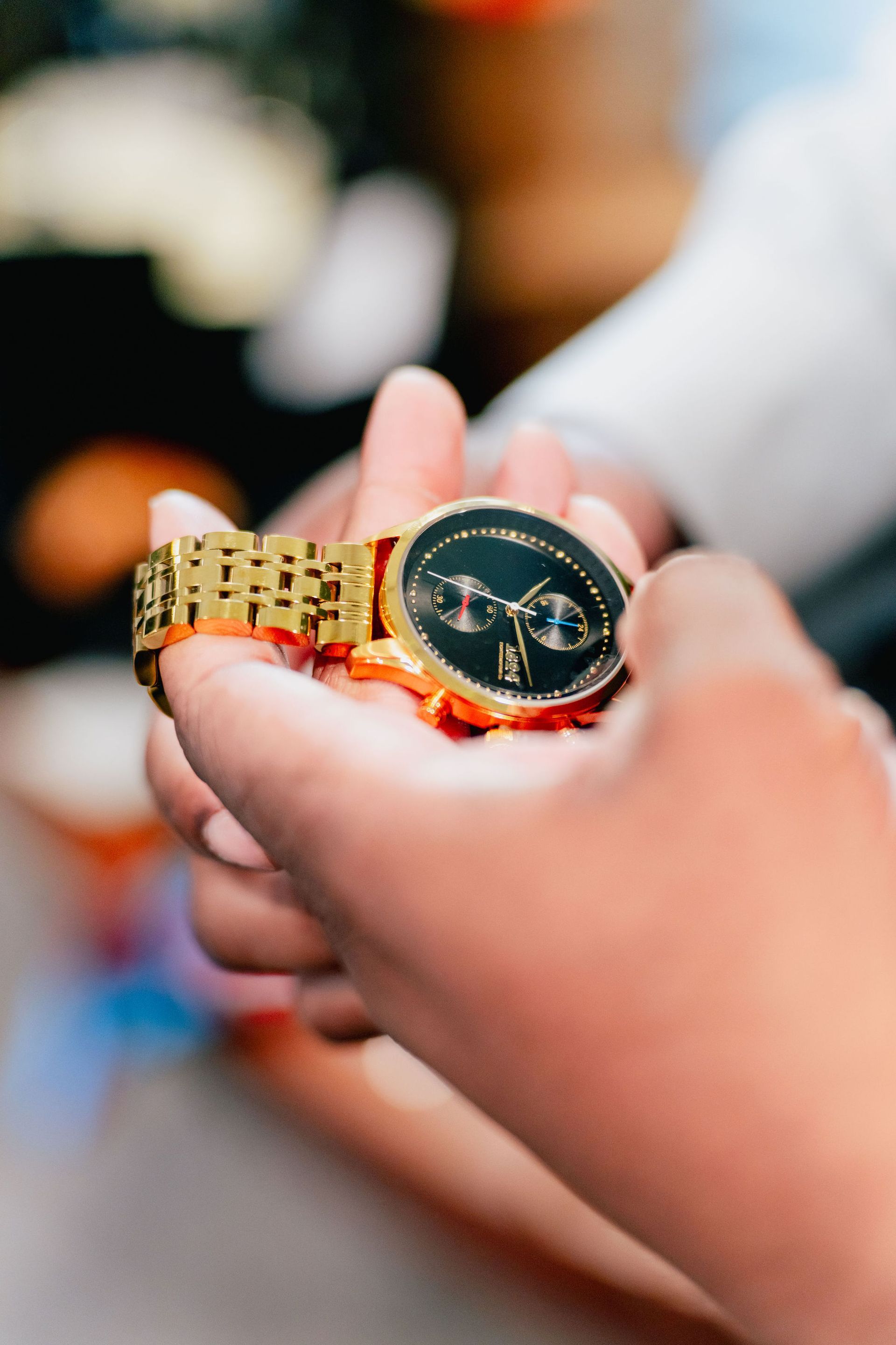 A person is holding a gold watch in their hand