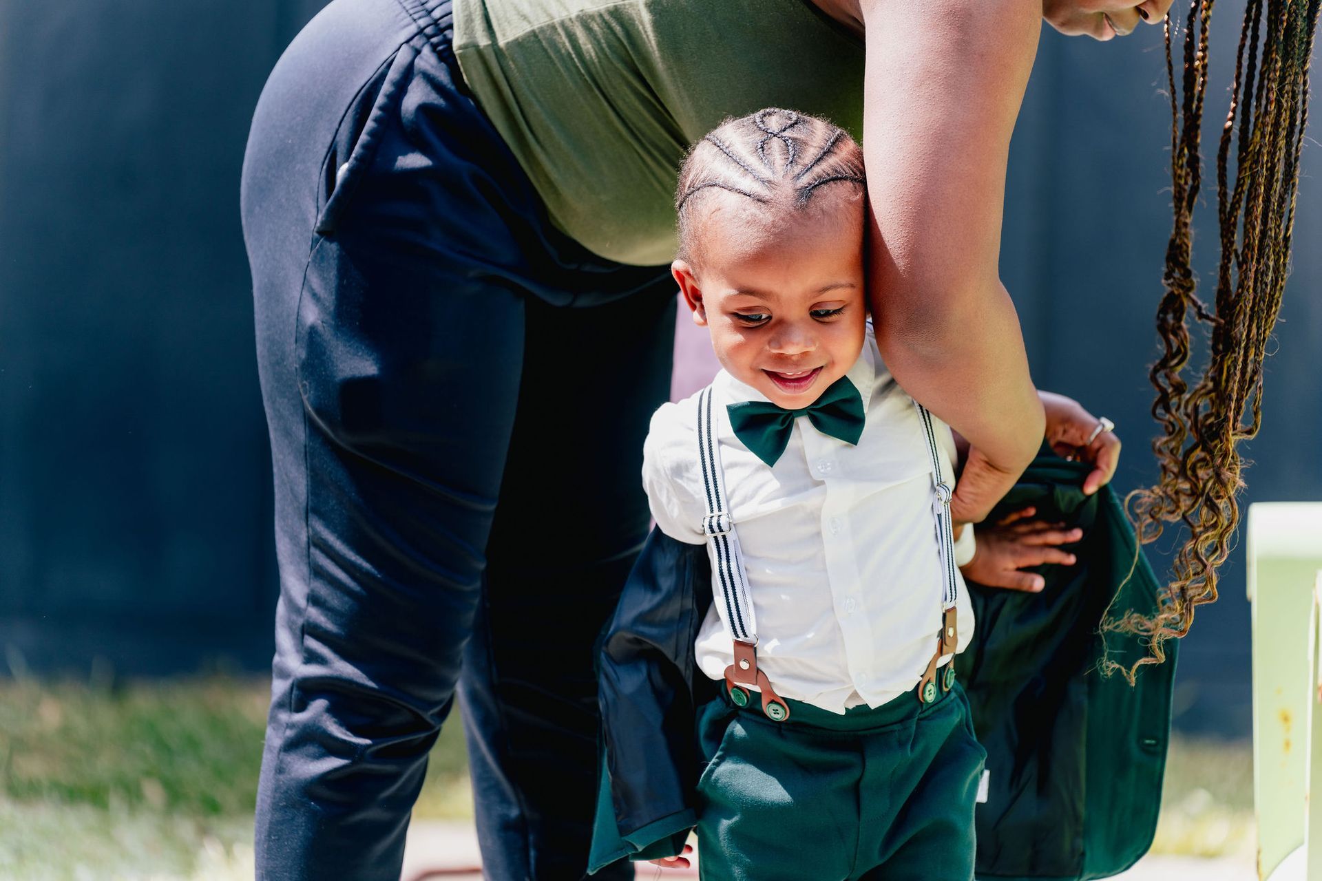 A woman is holding a little boy in a suit and bow tie.