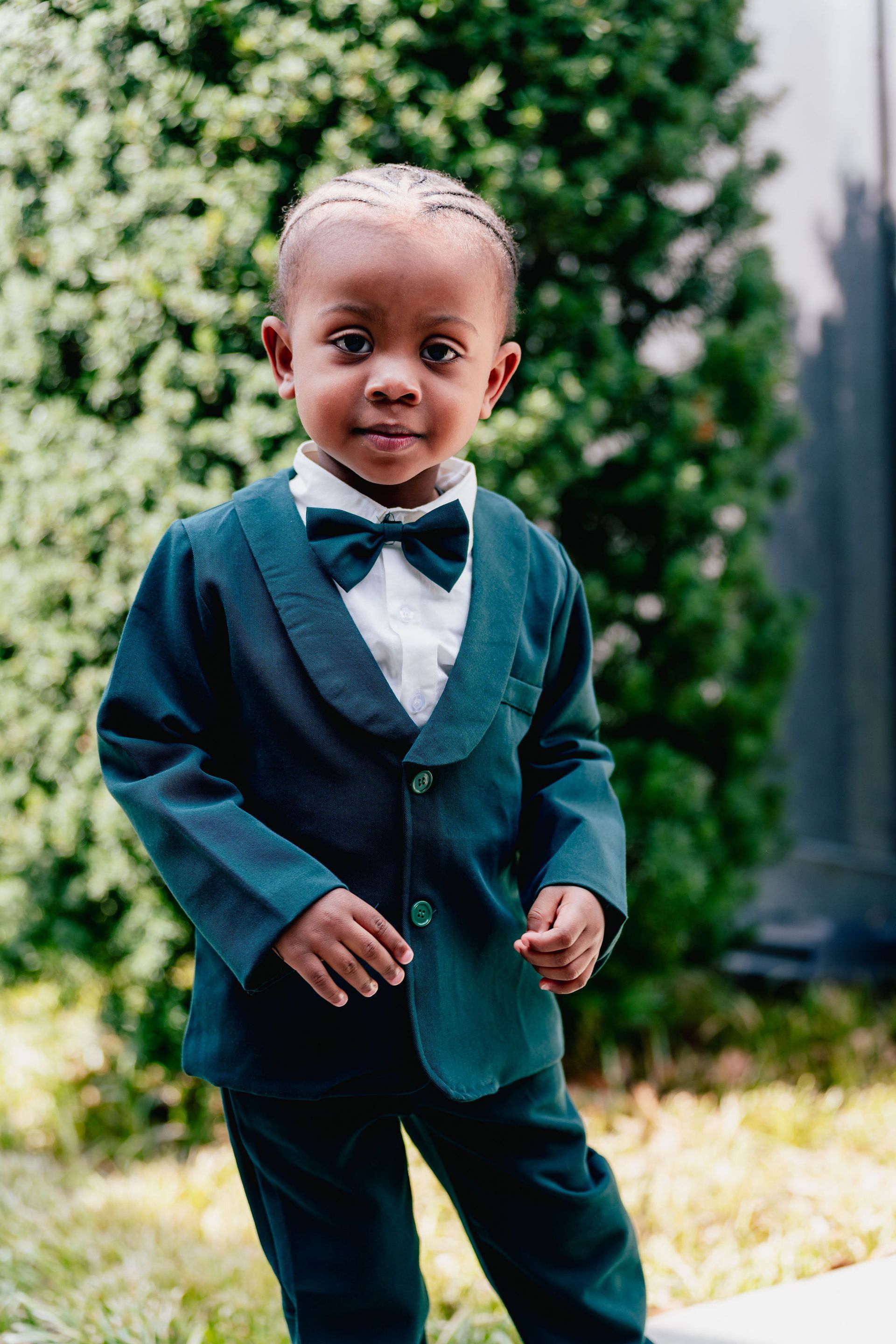 A little boy is wearing a green suit and bow tie.