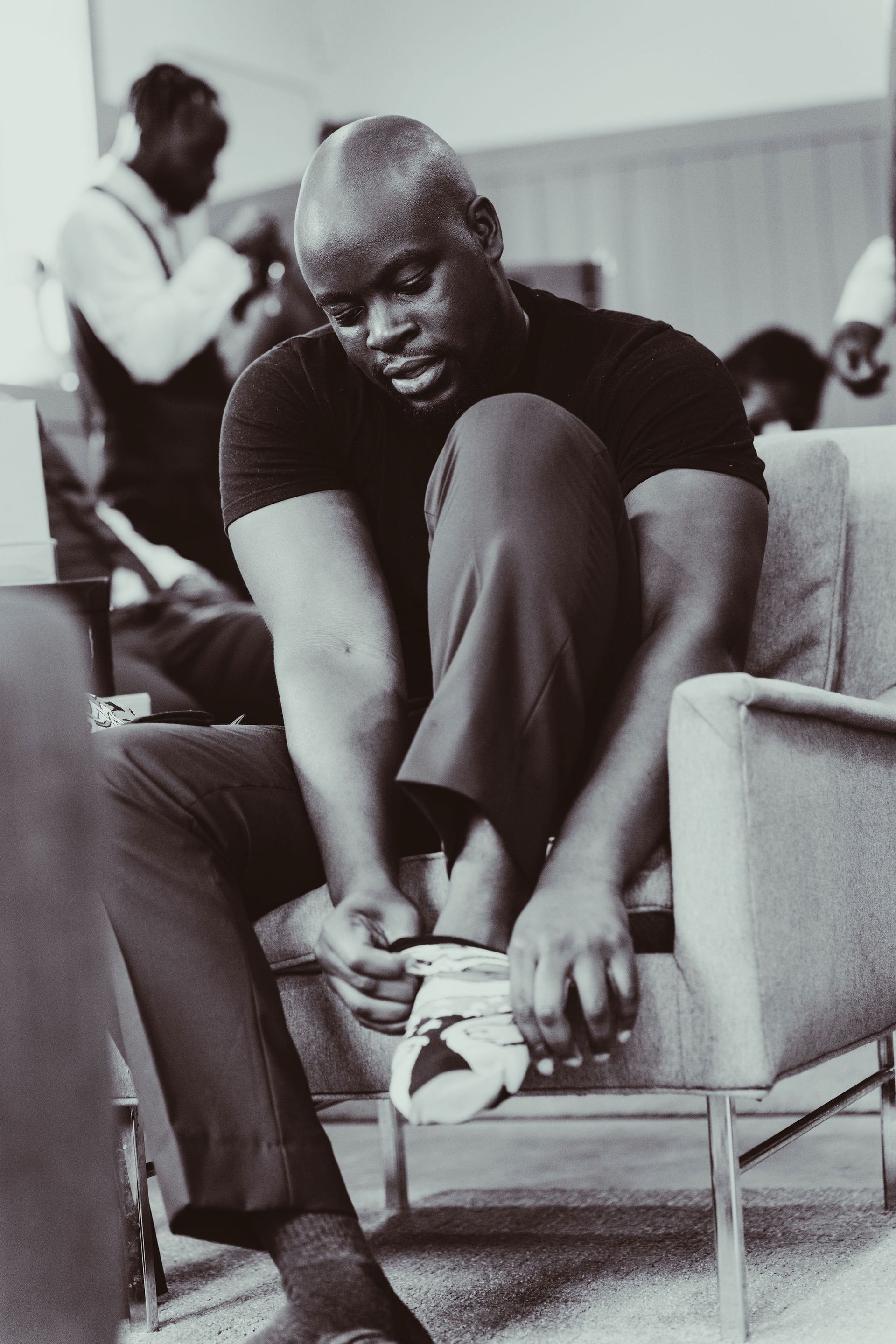 A black and white photo of a man tying his shoes