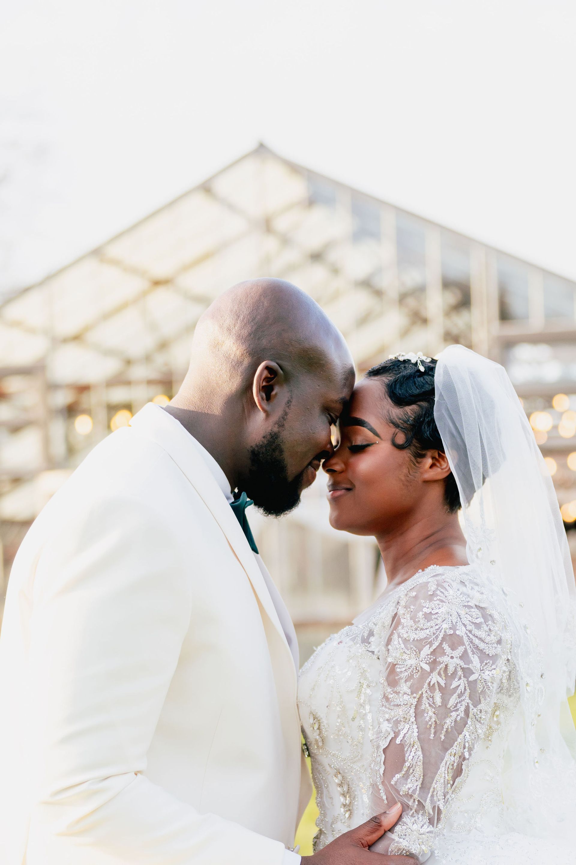 A bride and groom are touching their foreheads and looking at each other.