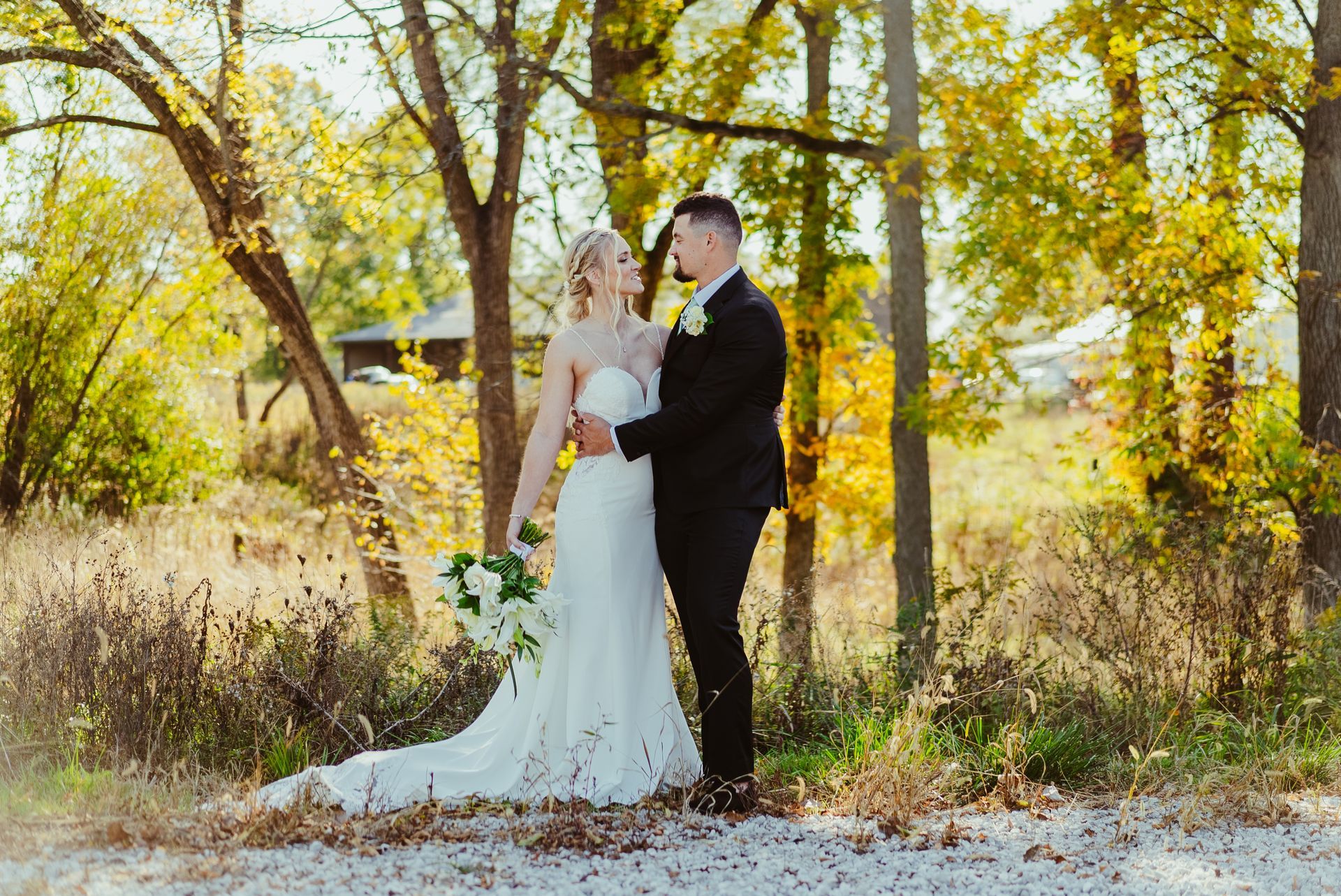 A bride and groom are posing for a picture in the woods.