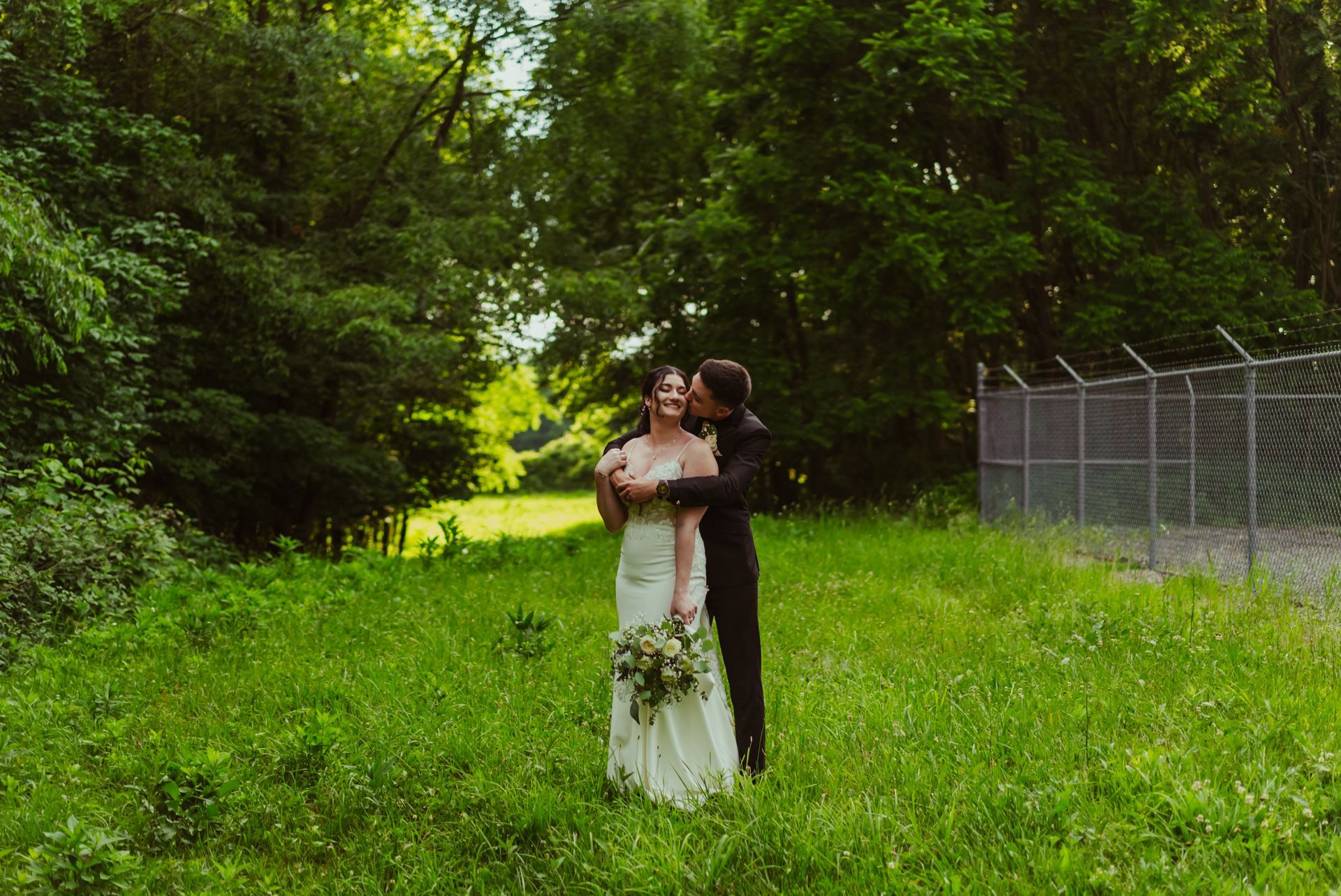 A bride and groom are posing for a picture in a field.