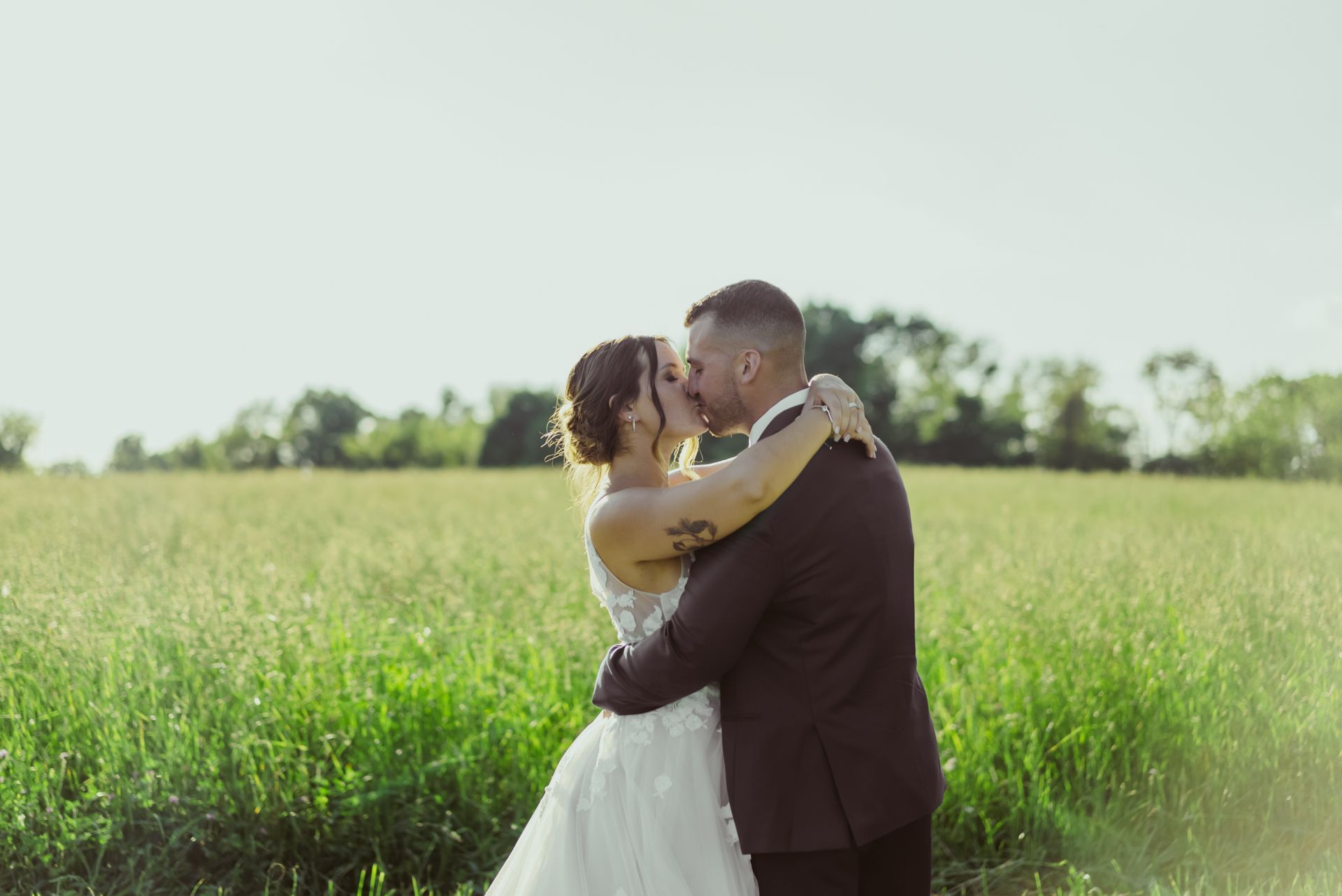 A bride and groom are kissing in a field.