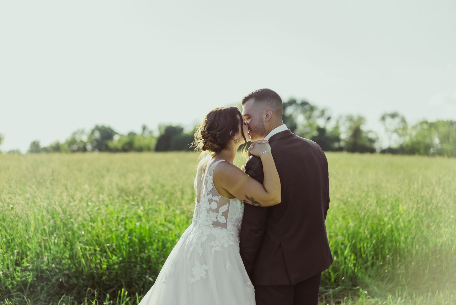 A bride and groom are kissing in a field.