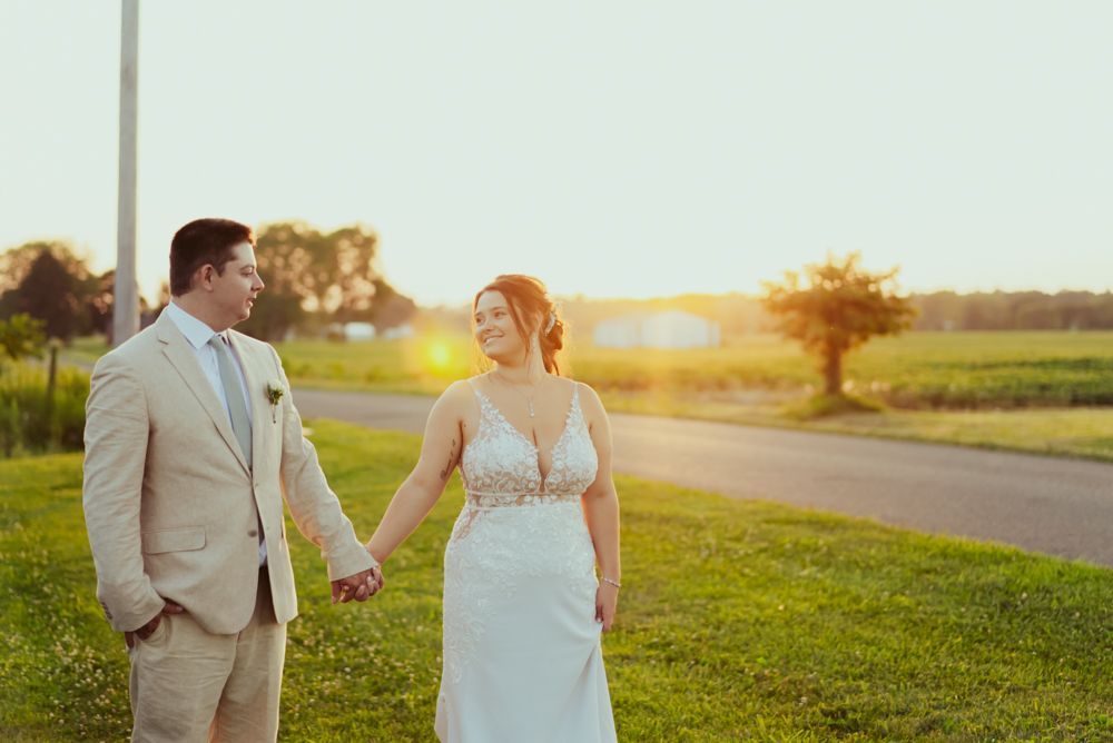 A bride and groom are holding hands in a field at their wedding at four season barn