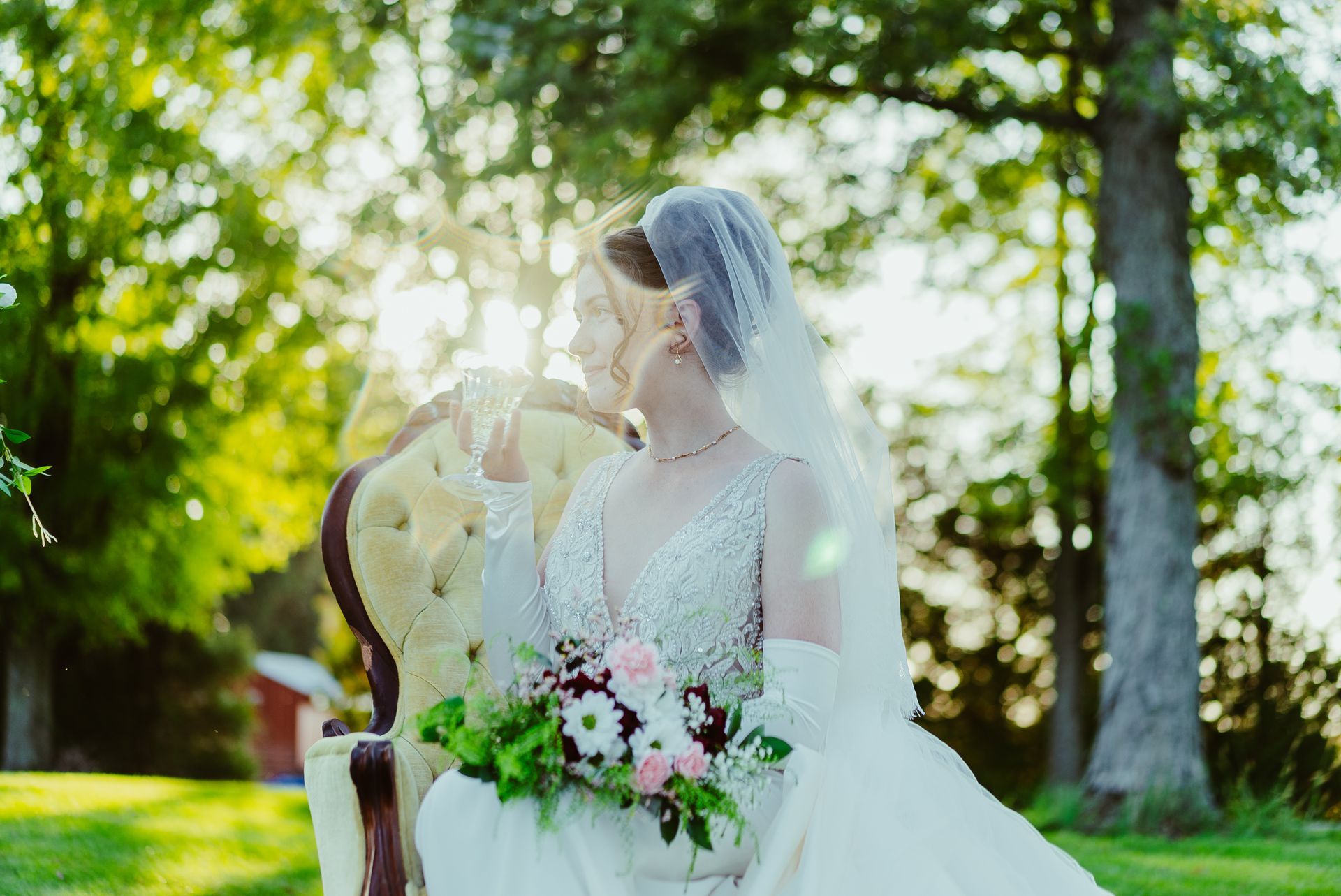 A bride in a wedding dress is sitting on a chair holding a bouquet of flowers.