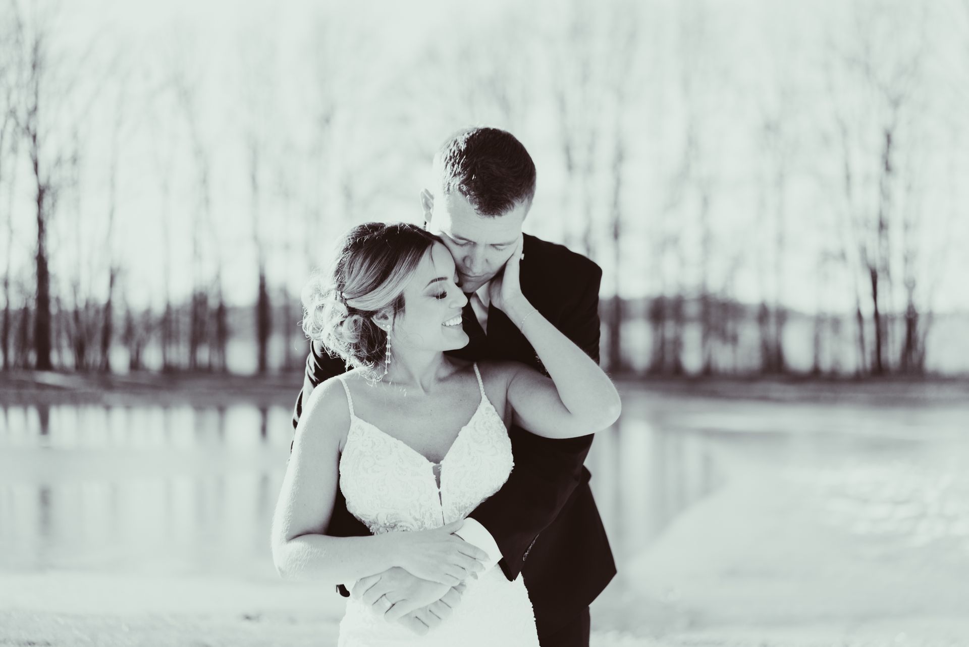 A camera is sitting on a bed next to a book of wedding photos.