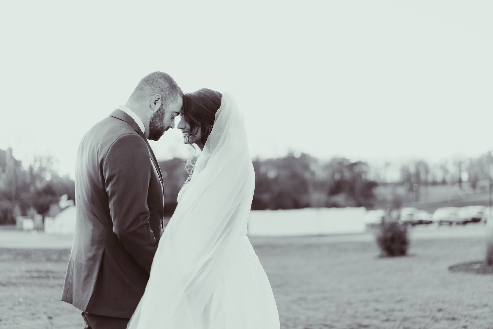 A bride and groom are standing next to each other in a field.