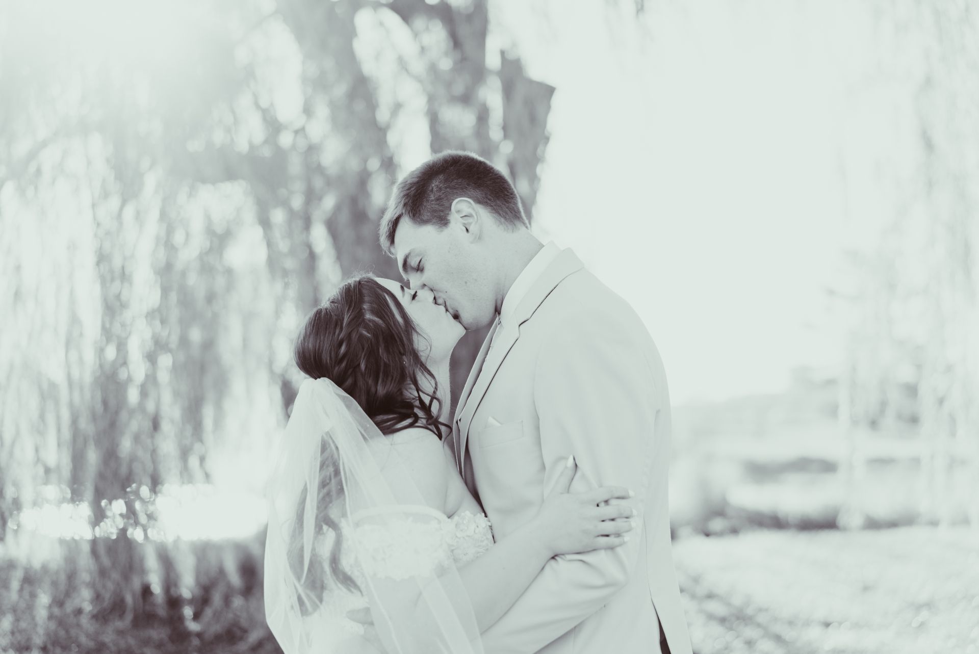 A bride and groom are kissing in a black and white photo.