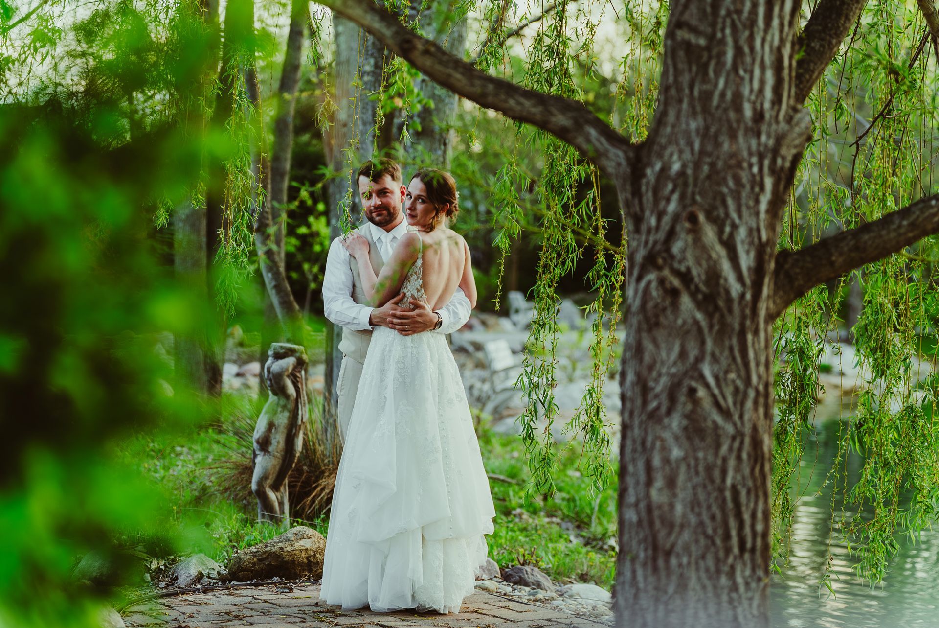 A bride and groom are standing next to a tree in the woods at Swanlake wedding venue in Hilliard Oh.