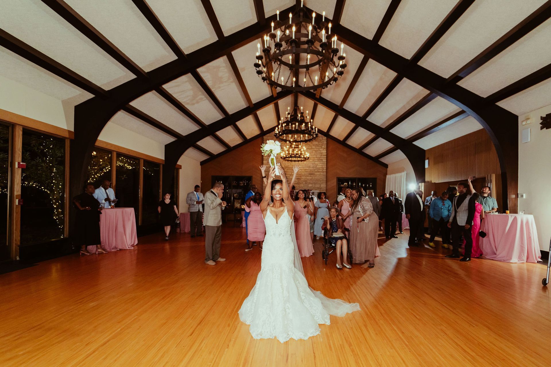 A bride is throwing her bouquet of flowers in a large room.
