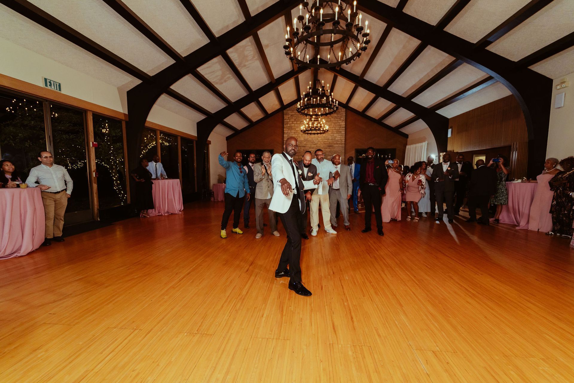 A man is dancing in a large room with a chandelier.