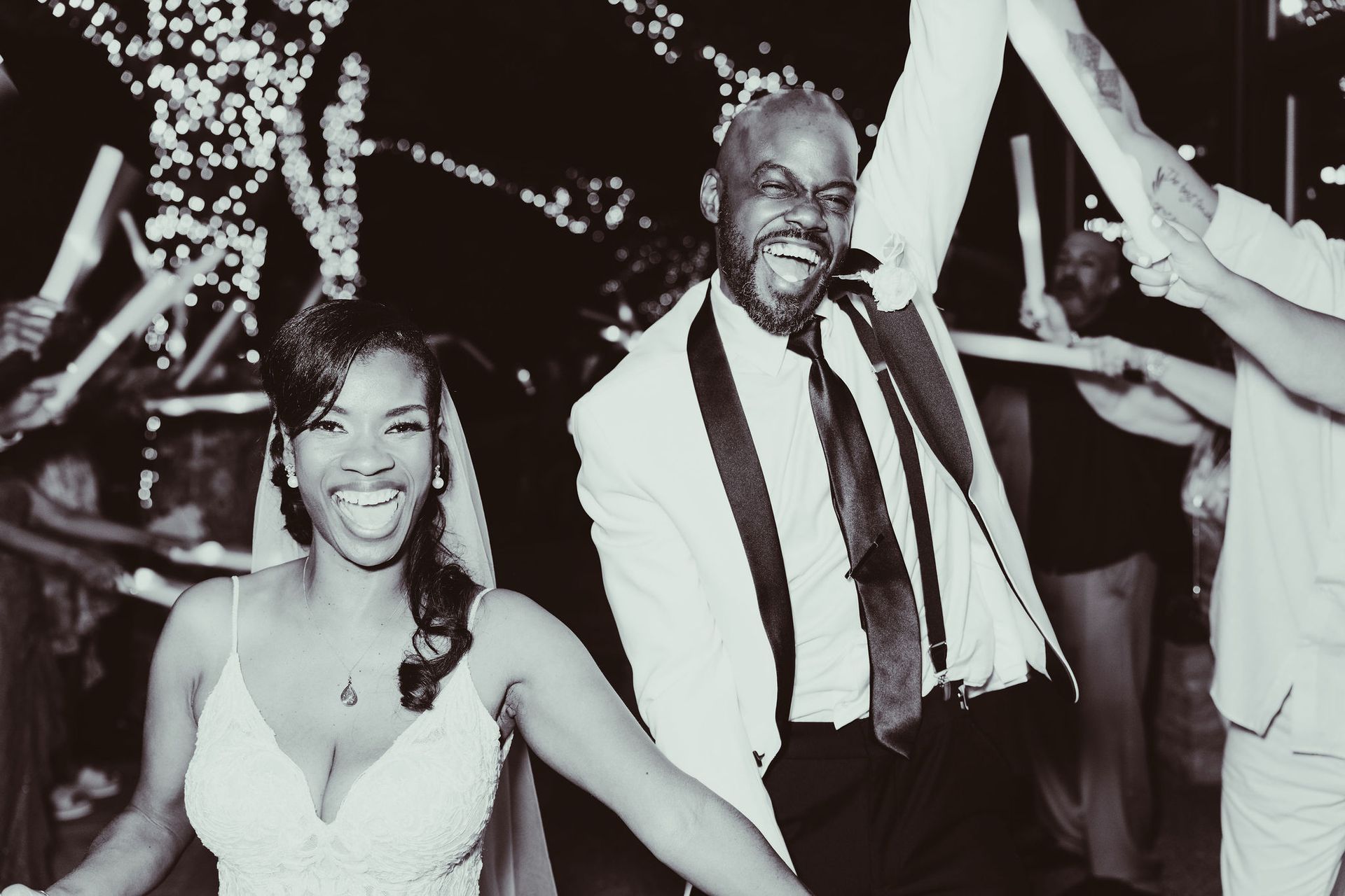 A black and white photo of a bride and groom holding hands