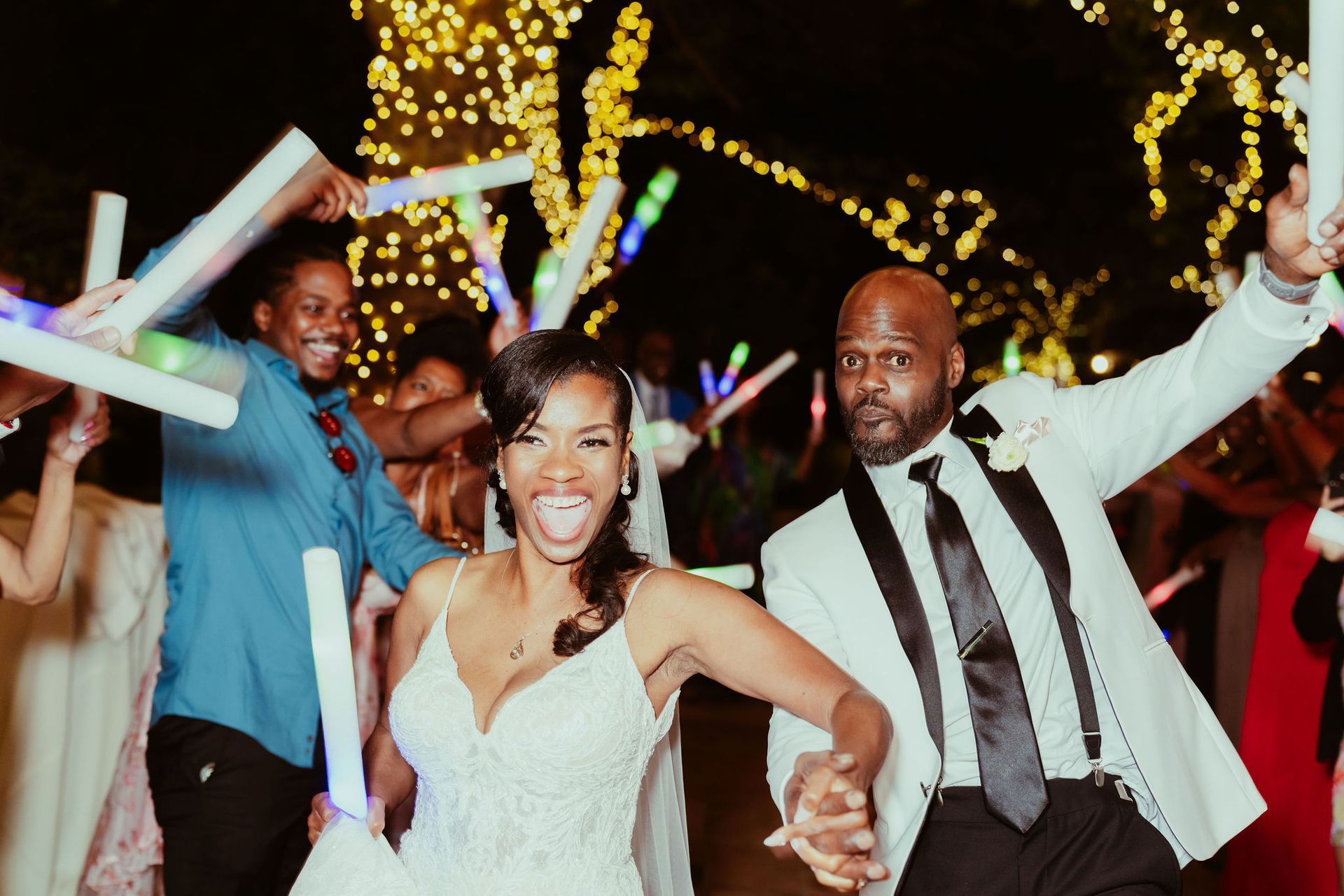 A bride and groom are dancing with glow in the dark sticks at their wedding reception.