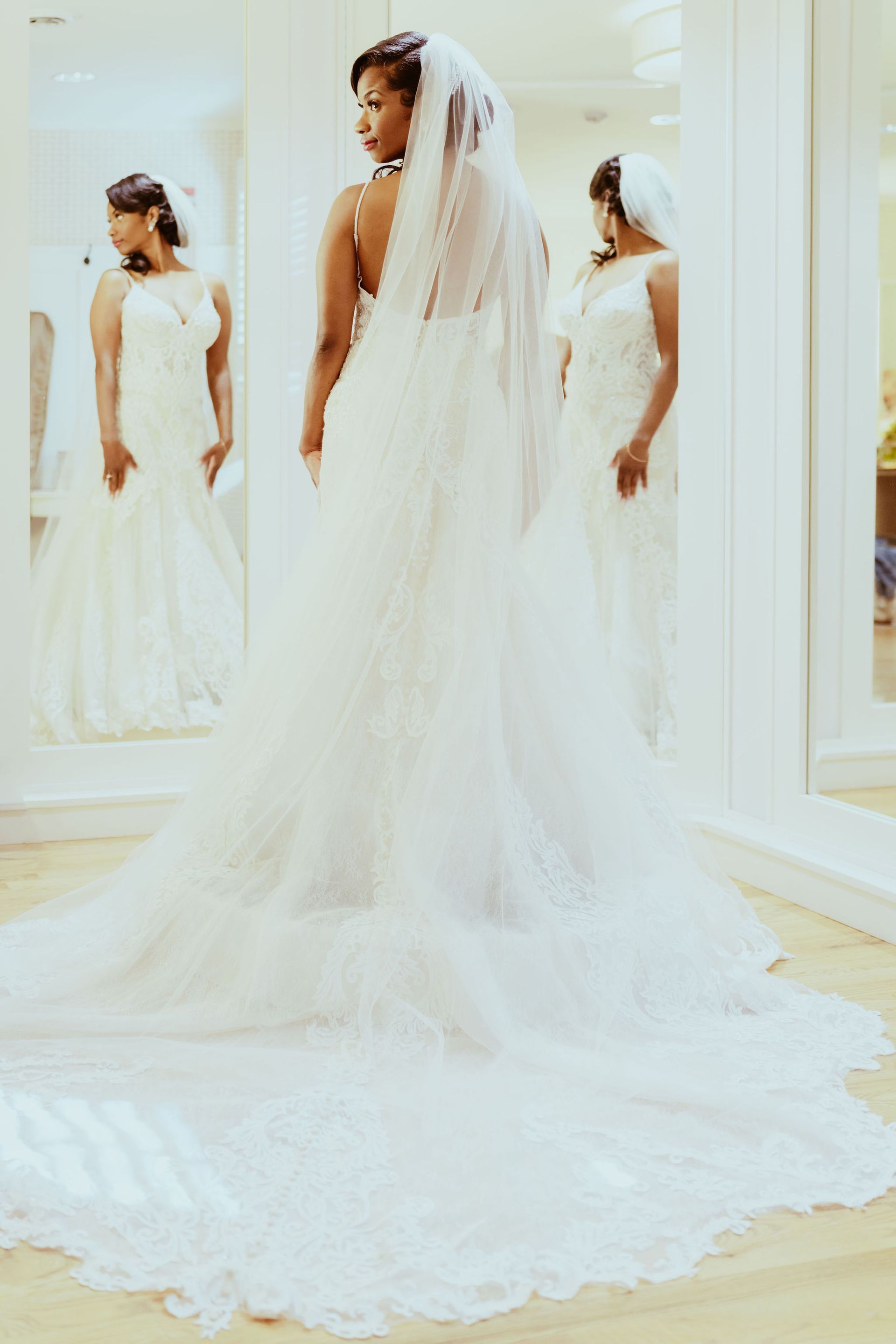 A woman in a wedding dress is standing in front of a mirror.