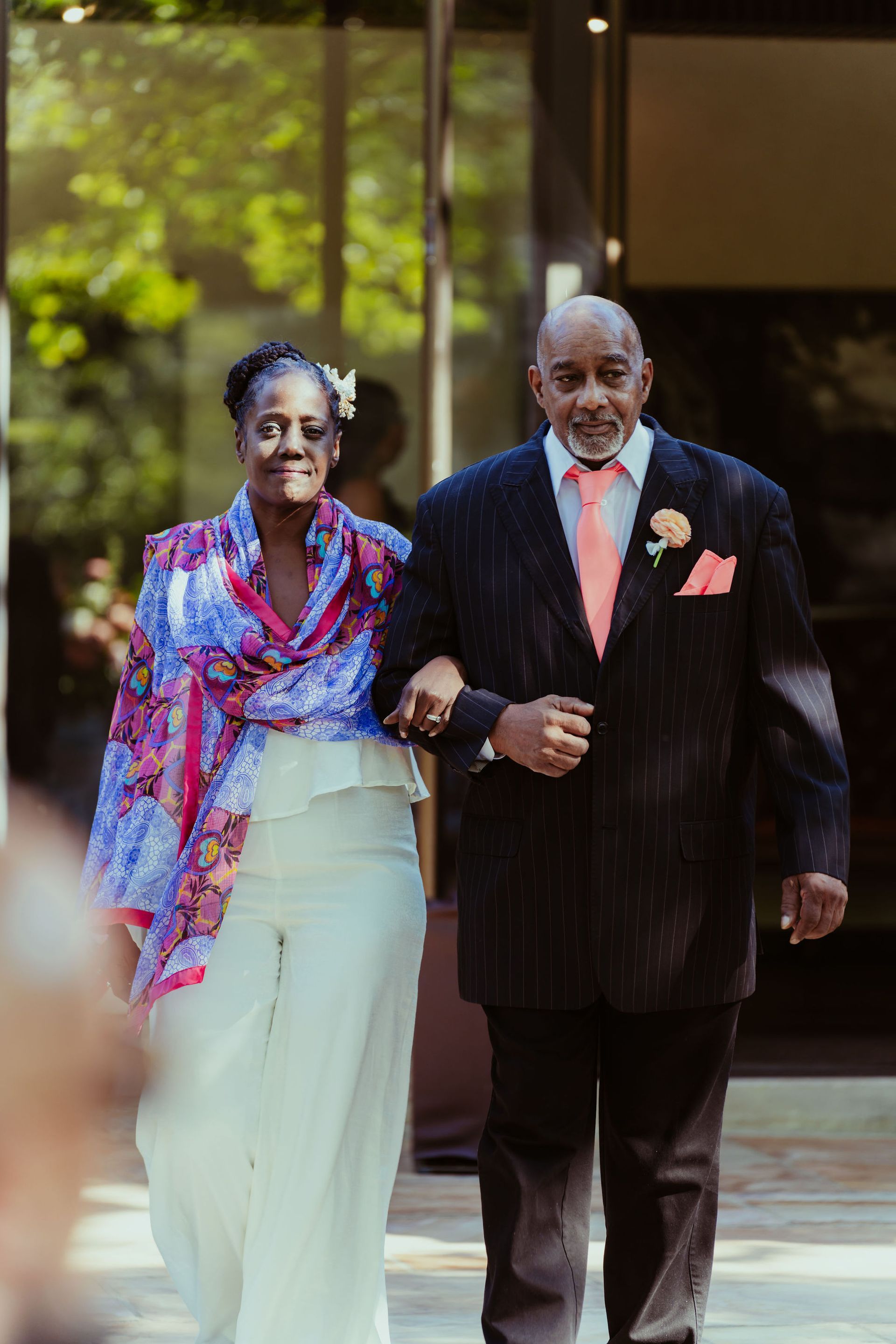 A man in a suit is walking a woman down the aisle at a wedding.