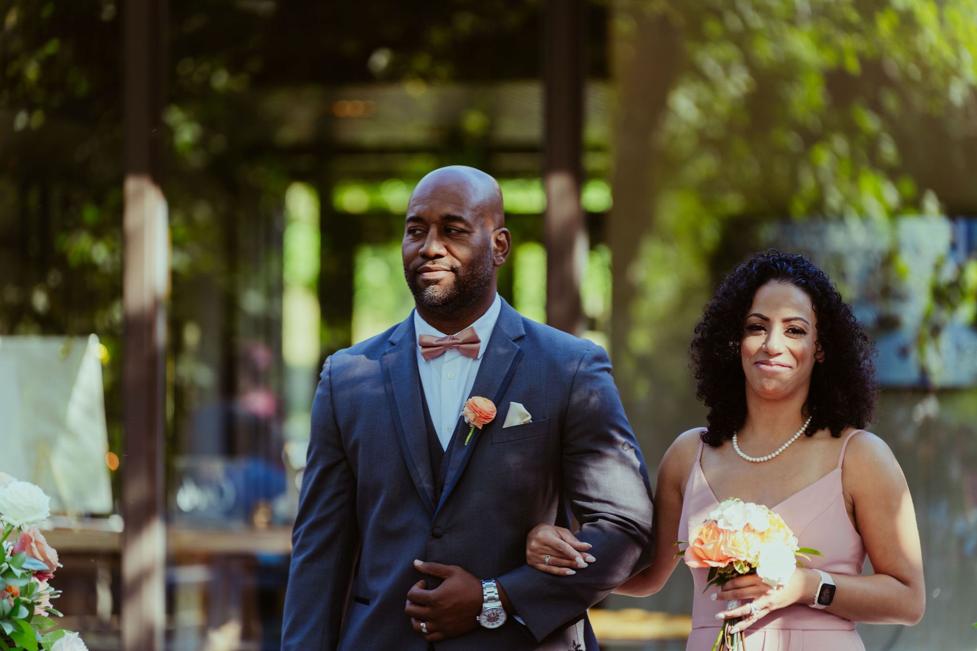 A man in a suit is walking down the aisle with a woman in a pink dress.