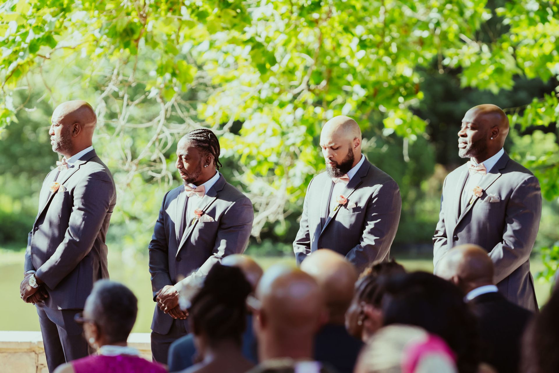 A group of men in suits and bow ties are standing in front of a crowd at a wedding ceremony.