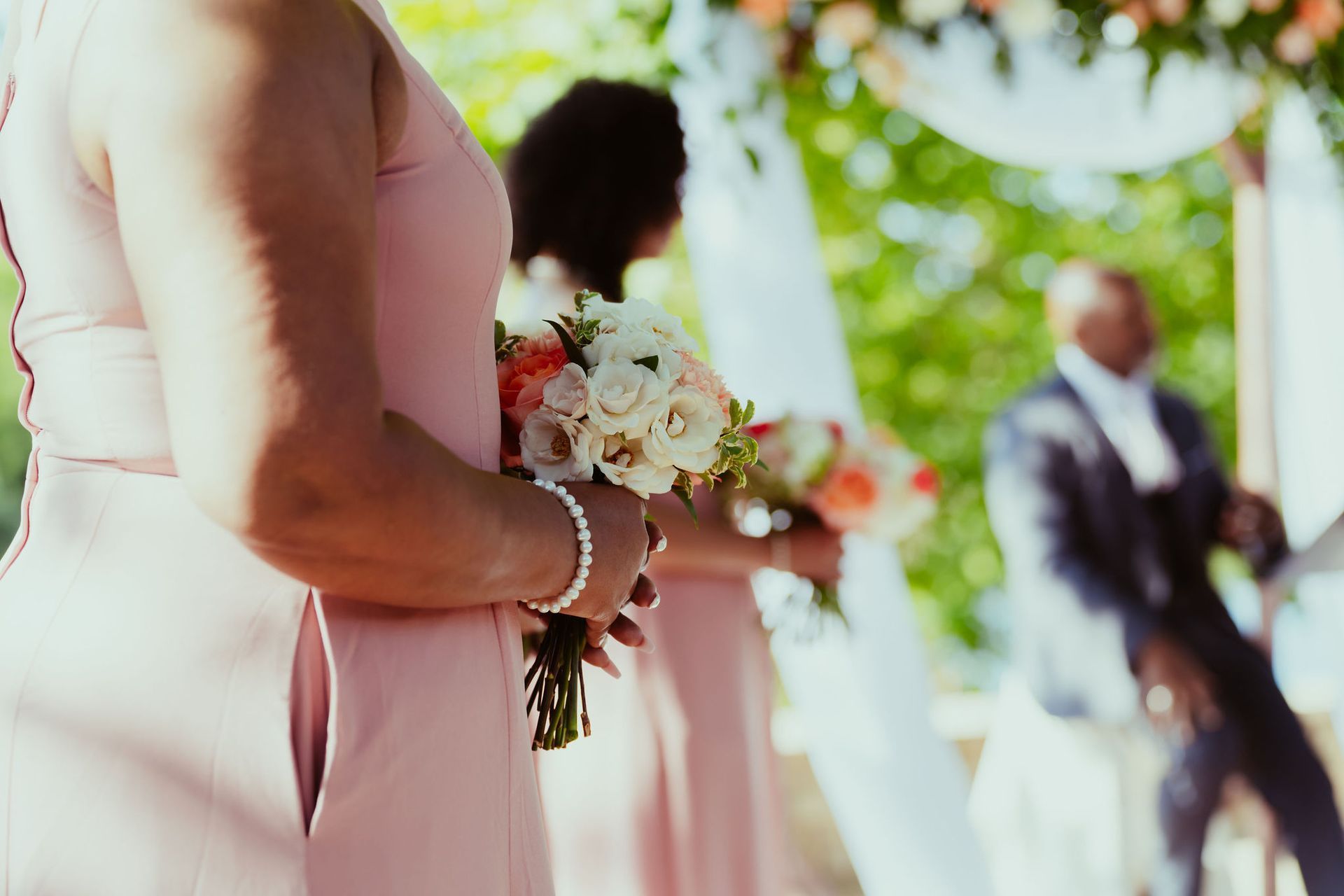 A woman in a pink dress is holding a bouquet of flowers.