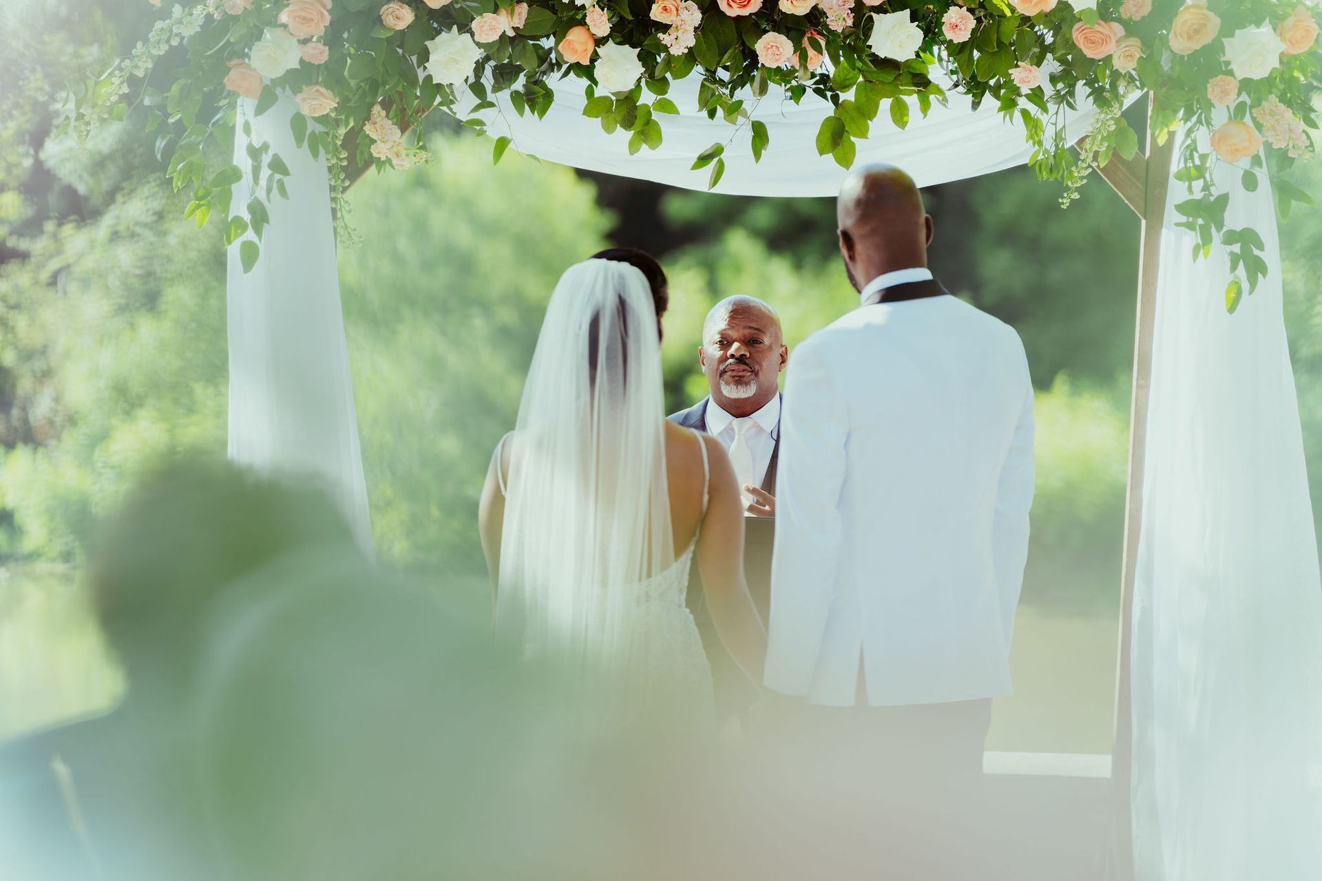 A bride and groom are standing under a canopy at their wedding ceremony.