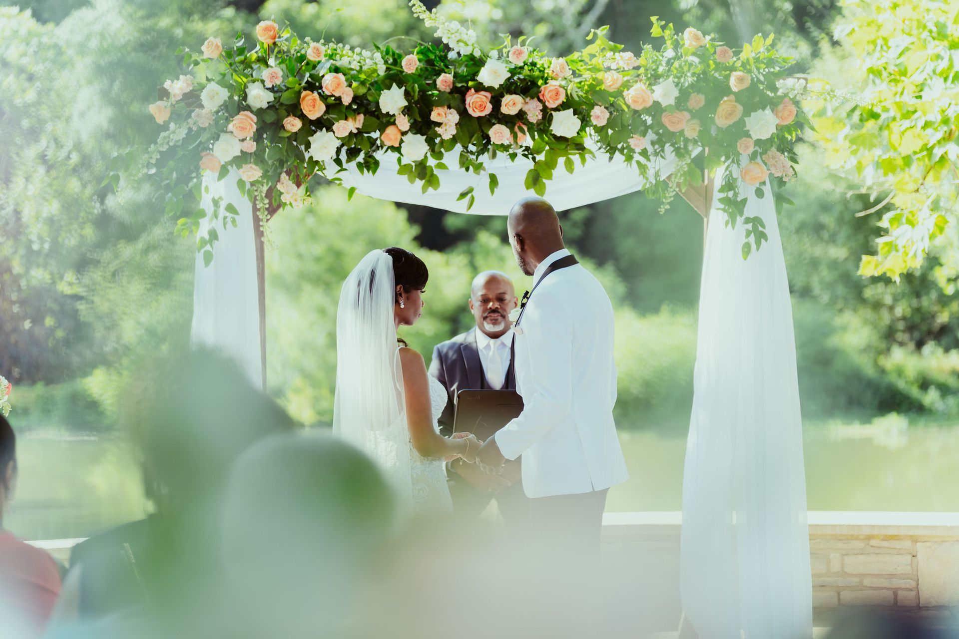 A bride and groom are getting married under a canopy with flowers.
