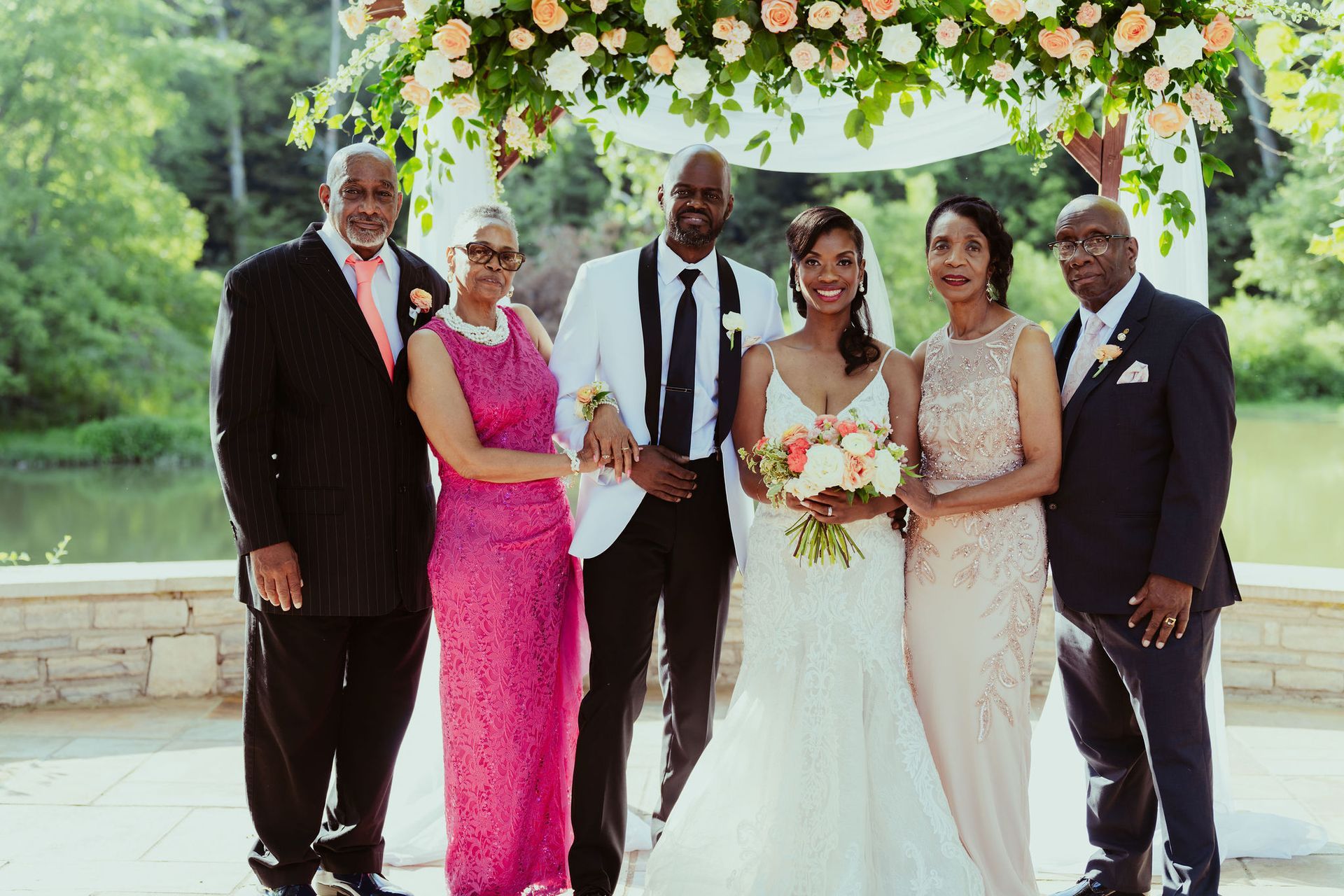 A bride and groom are posing for a picture with their parents at their wedding.
