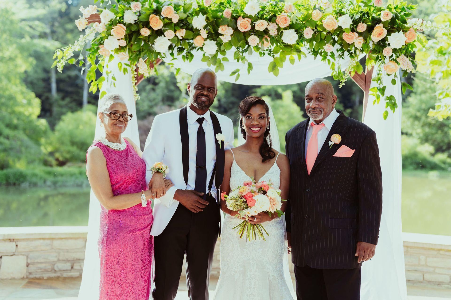 A bride and groom are posing for a picture with their parents at their wedding.