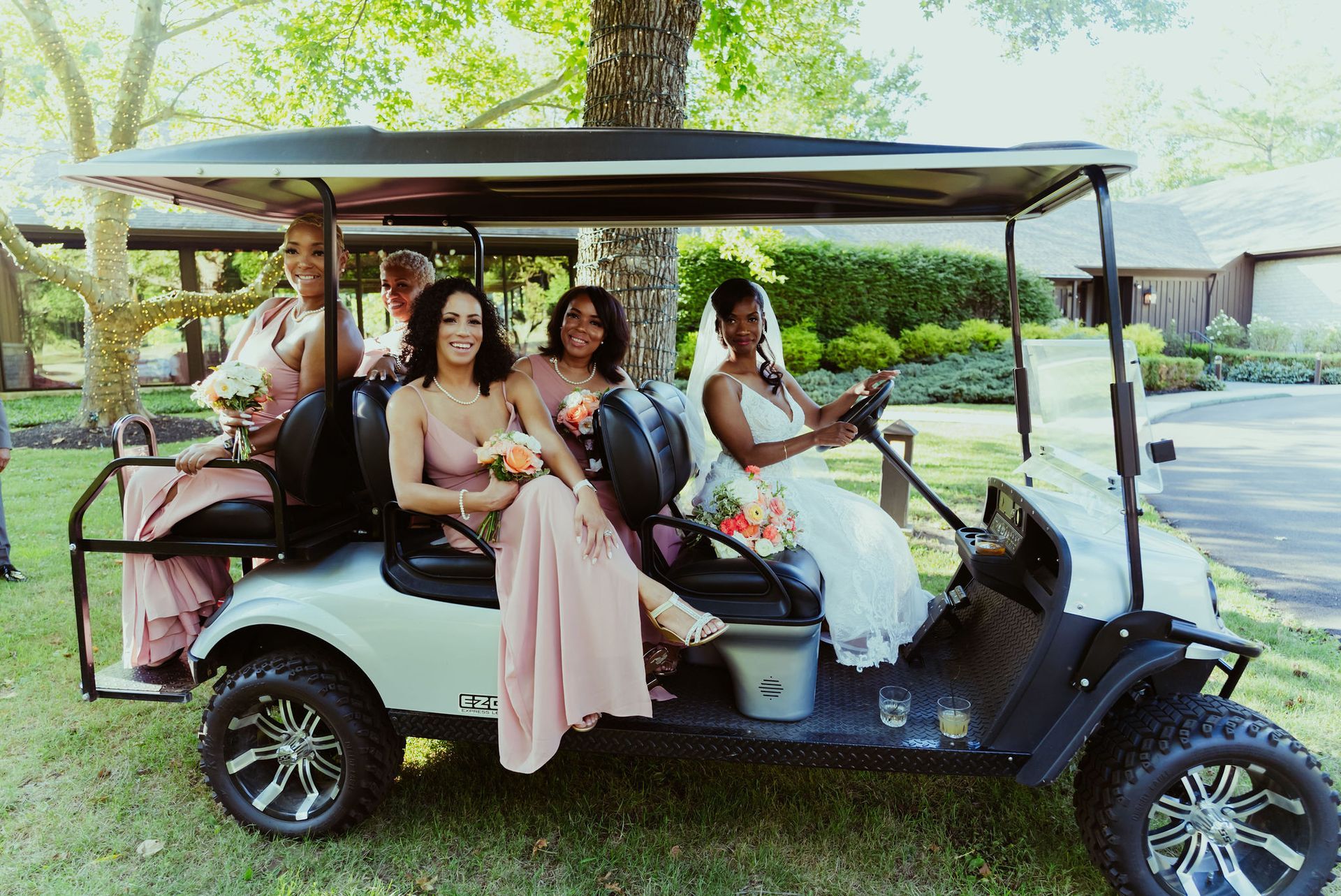 A bride and her bridesmaids are sitting in a golf cart.