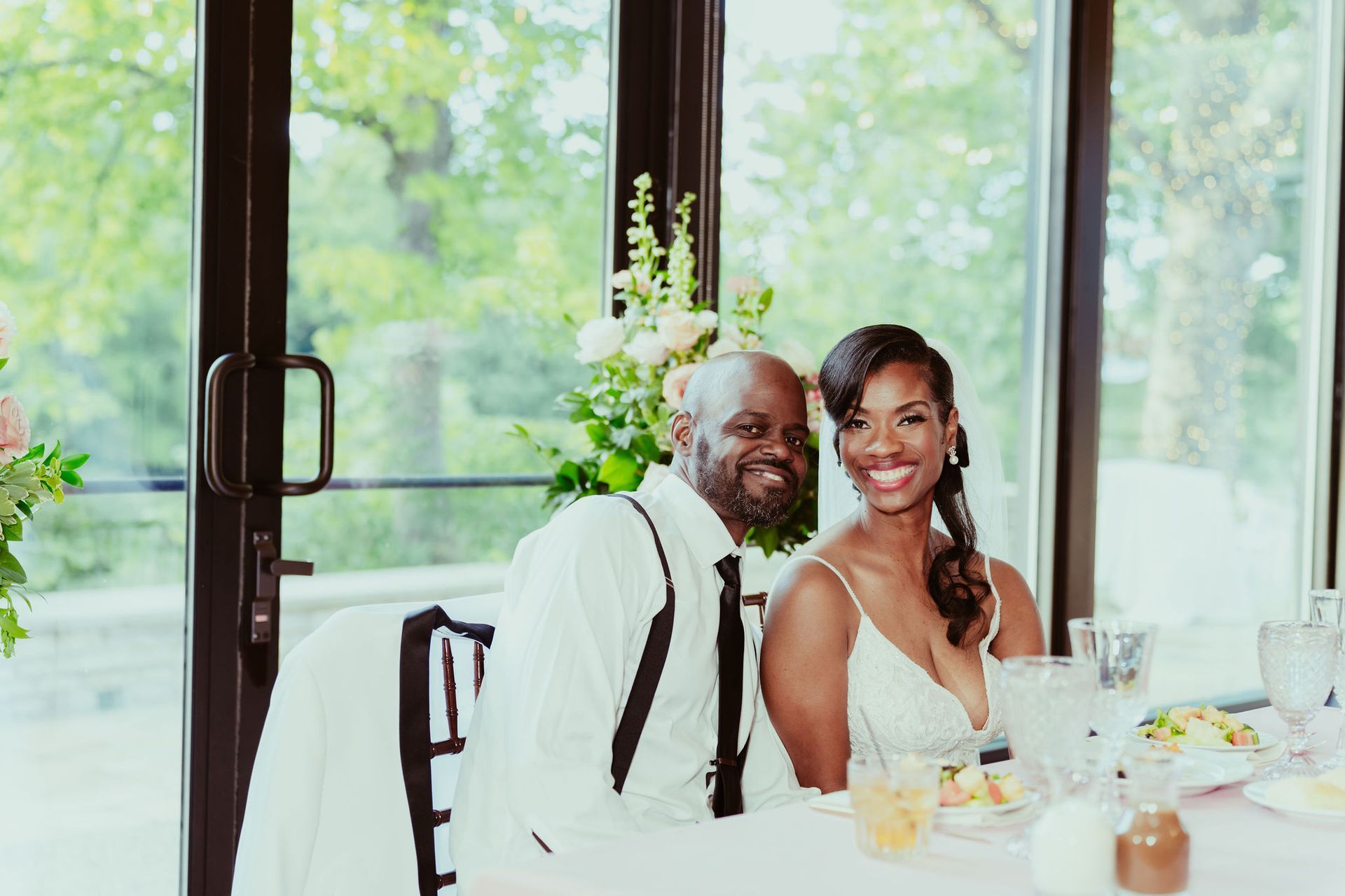 A bride and groom are sitting at a table at a wedding reception.