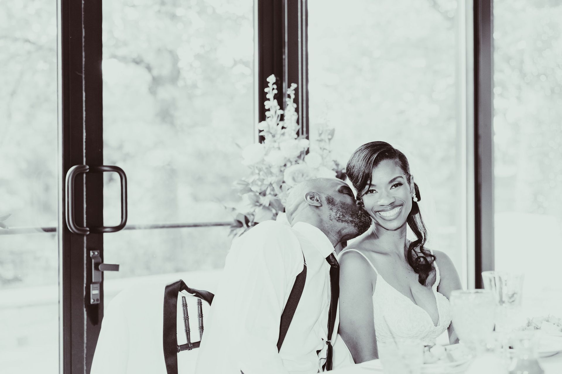 A man is kissing a woman on the cheek while sitting at a table.