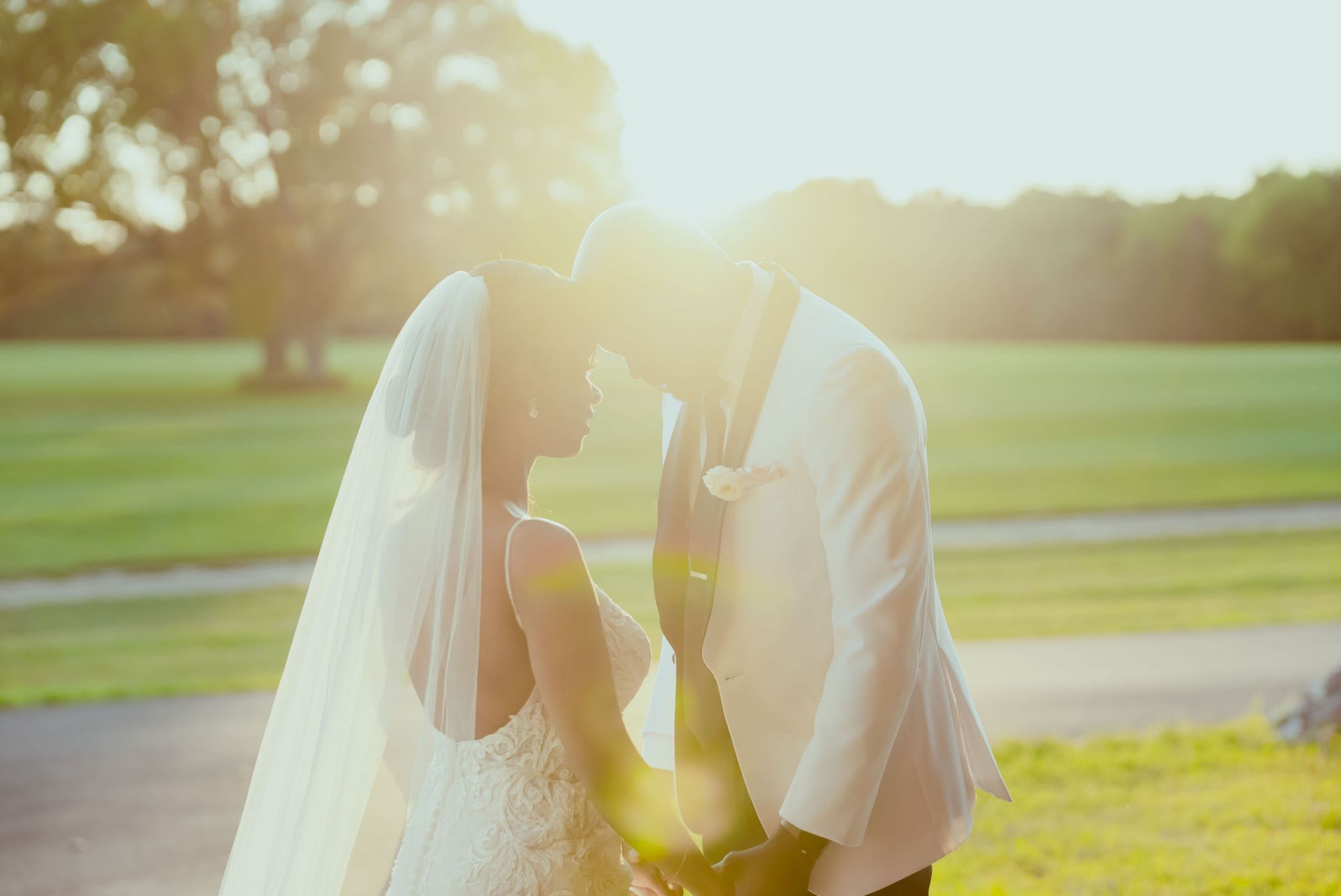 A bride and groom are kissing in a field at their wedding.