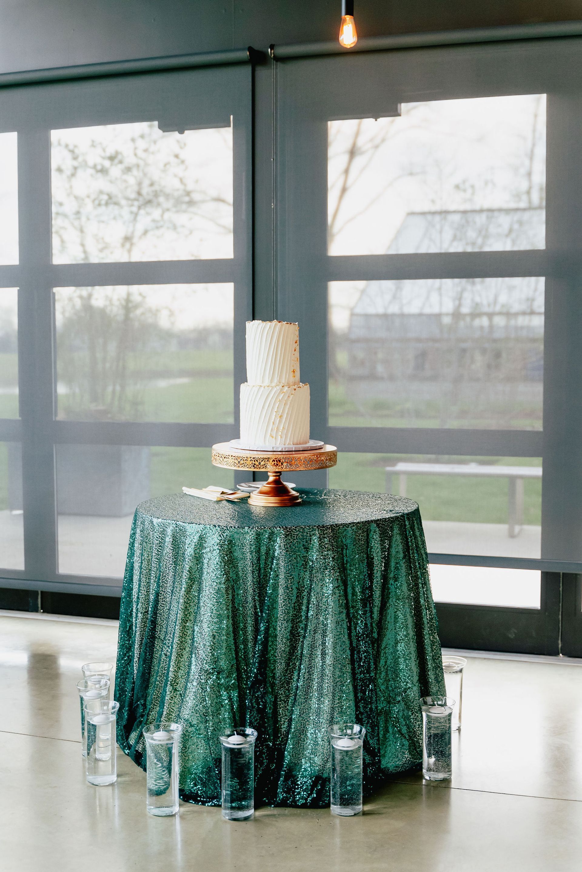 A white cake is sitting on top of a green sequined table cloth.
