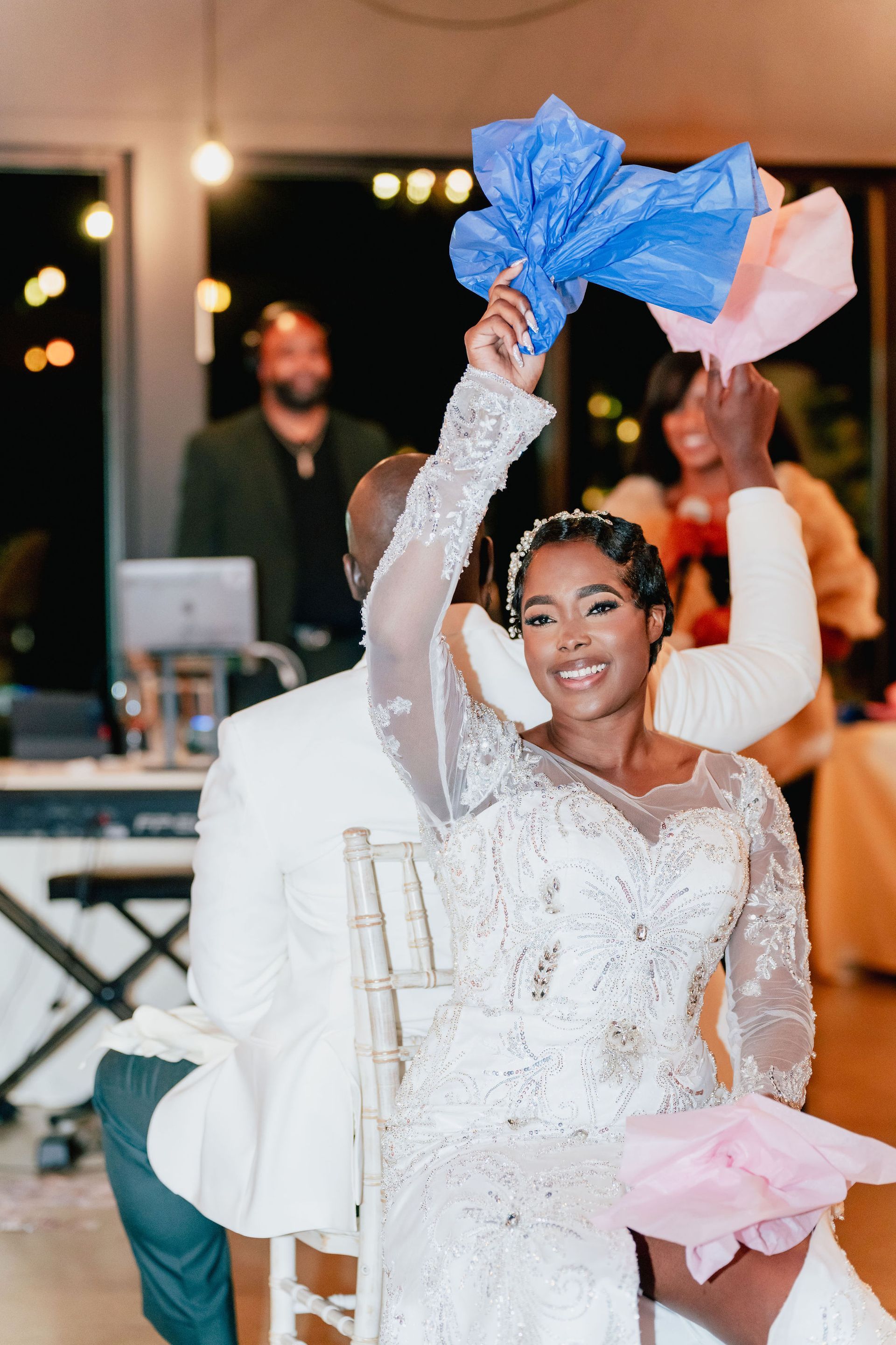 A bride and groom are sitting in chairs holding tissue paper.