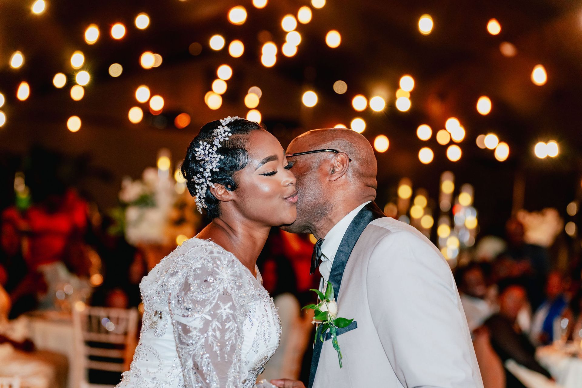 A bride and groom are kissing at their wedding reception.
