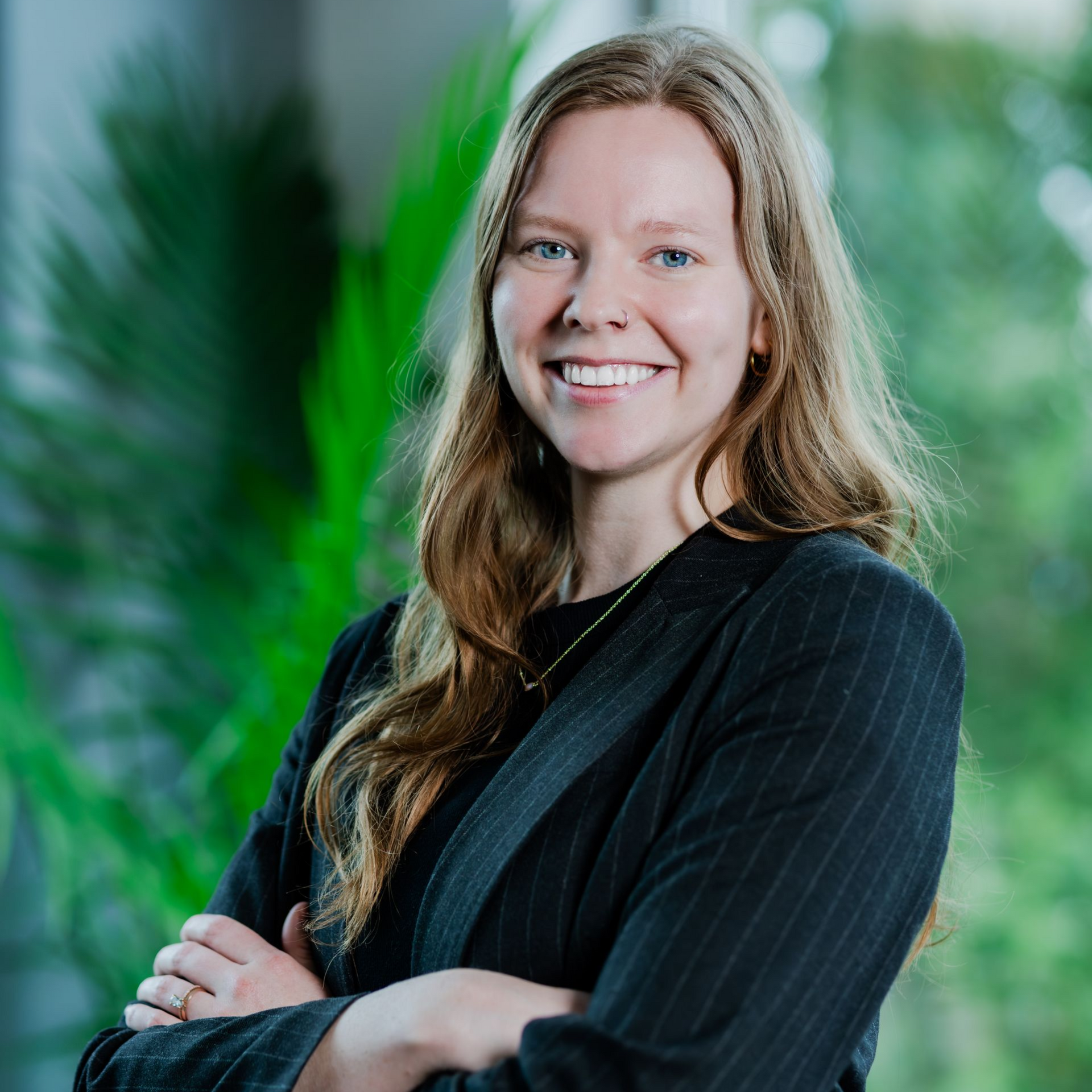 A woman in a black shirt is smiling with her arms crossed.