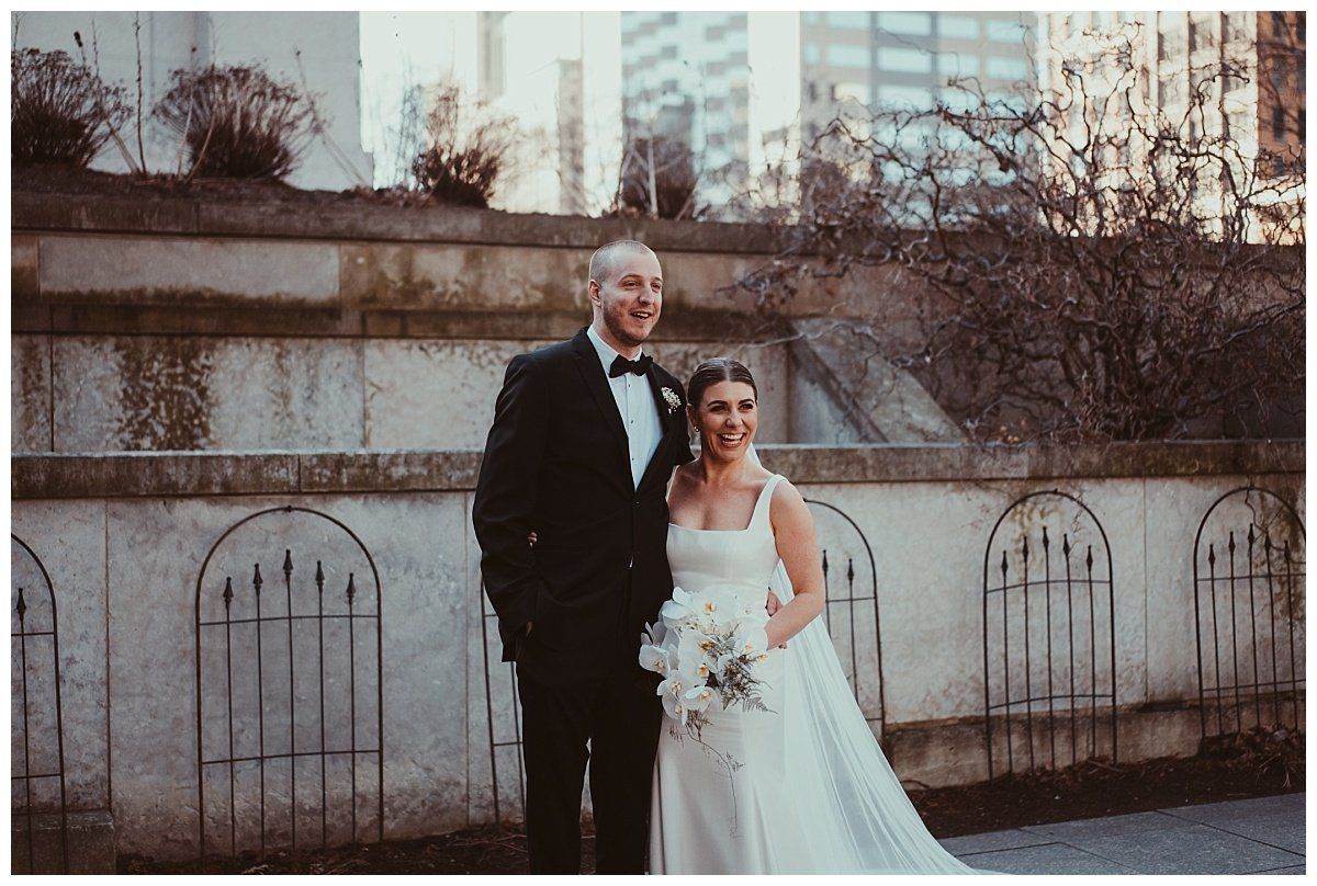 a bride and groom are posing for a picture in front of a building .