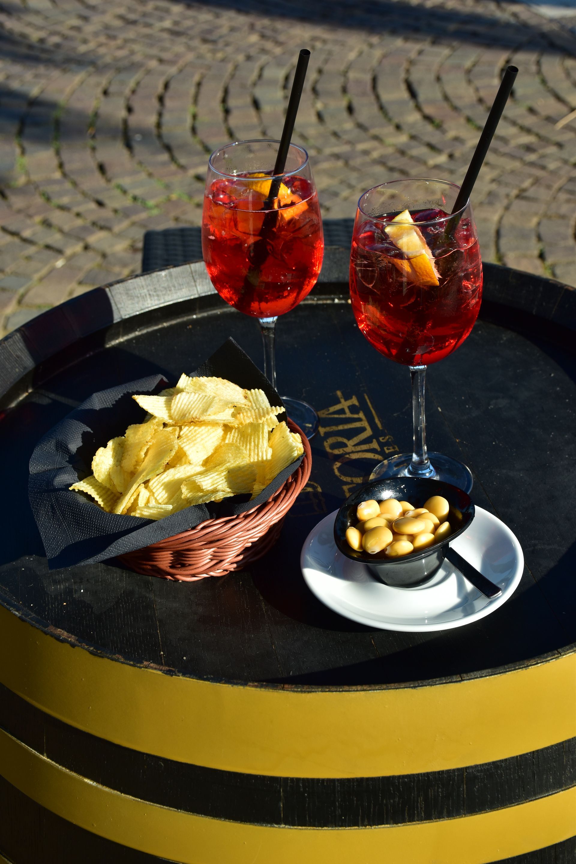 Due cocktail rossi con patatine e noci su un tavolo all'aperto.