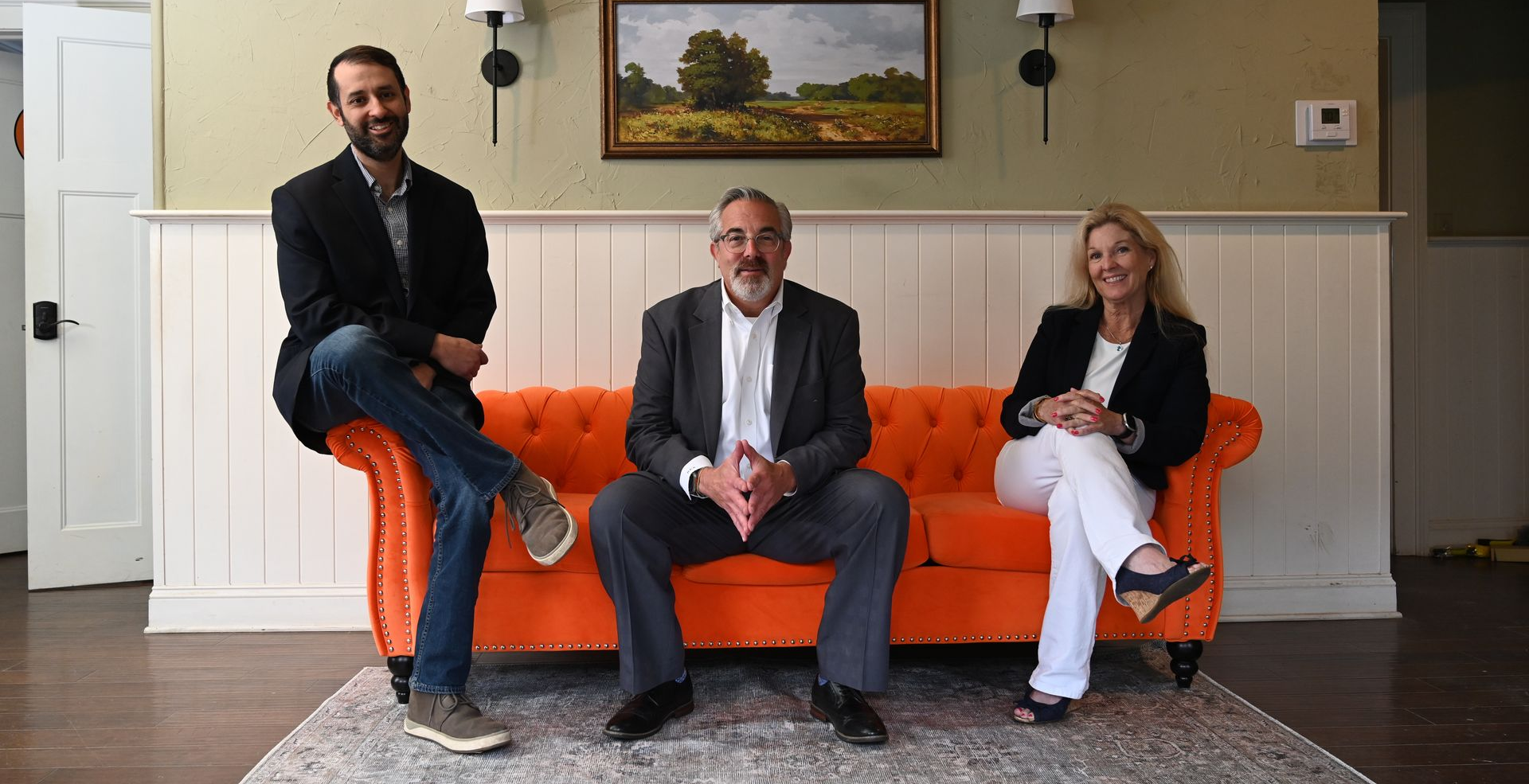 Attorney Robert Addelman and his team seated on an orange couch intheir office, posing for a photo.