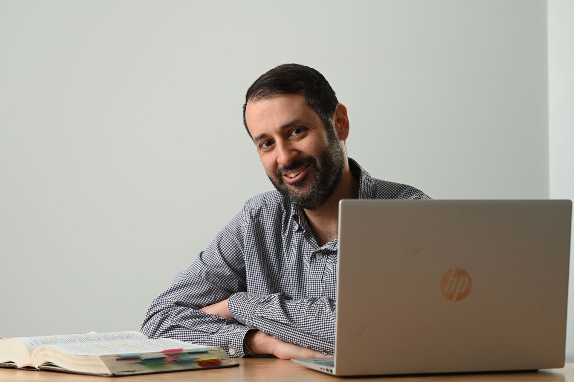 Jon Strano smiling beside a laptop reviewing a contract at a desk with papers in a bright room