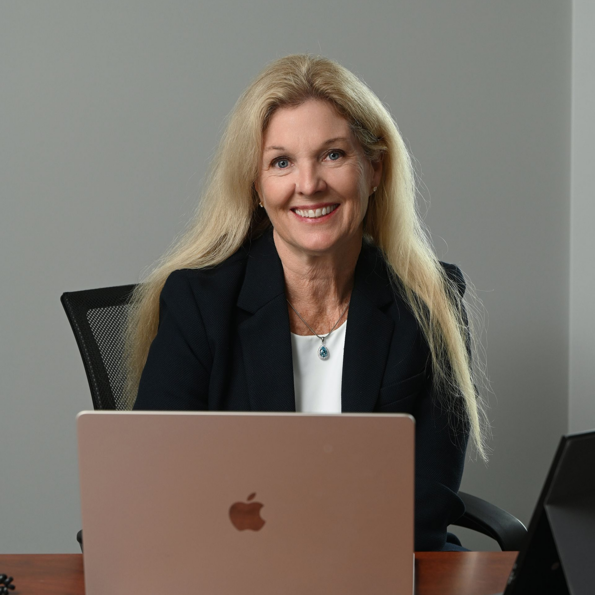 Woman smiling behind a laptop at a desk in an office meeting room