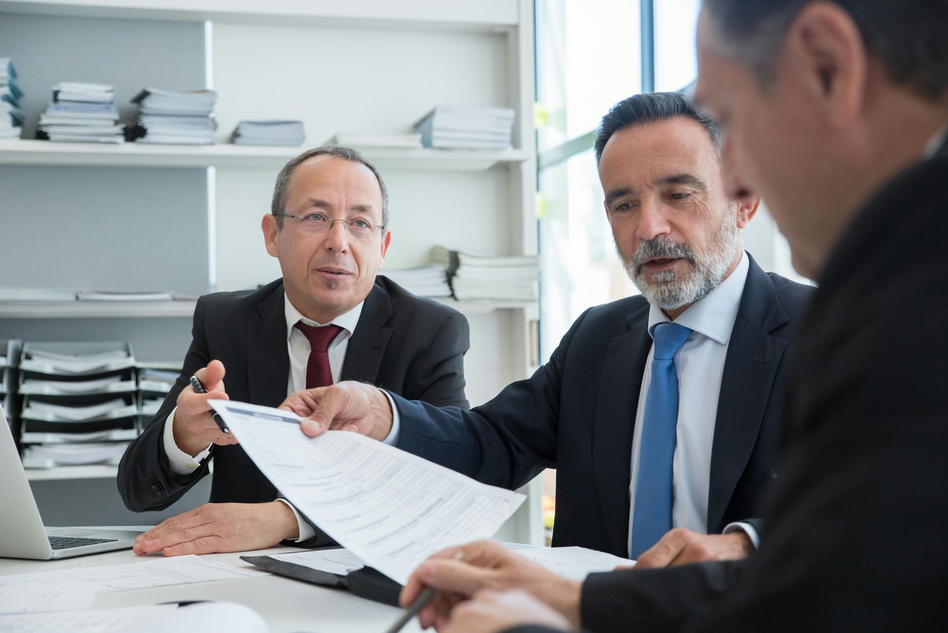 Three lawyers reviewing documents in a bright office meeting room