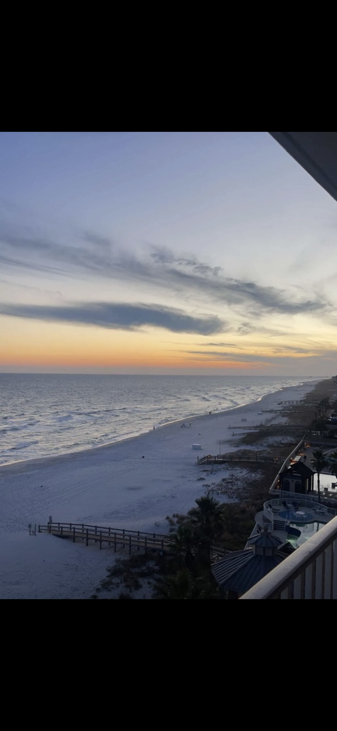 Lobby with green armchairs, large windows, and decorative chandelier.