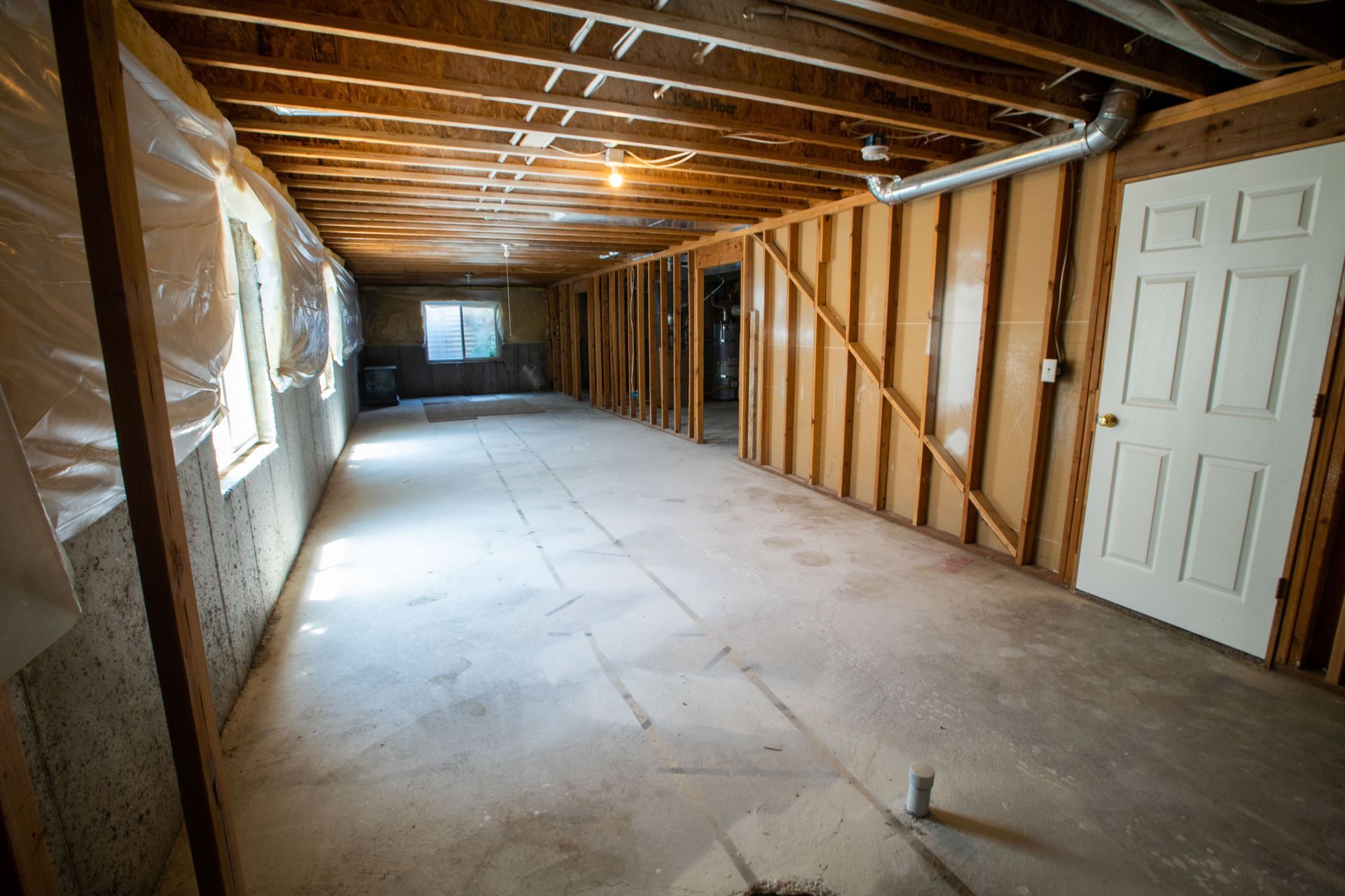 An empty basement with wooden walls and a white door.